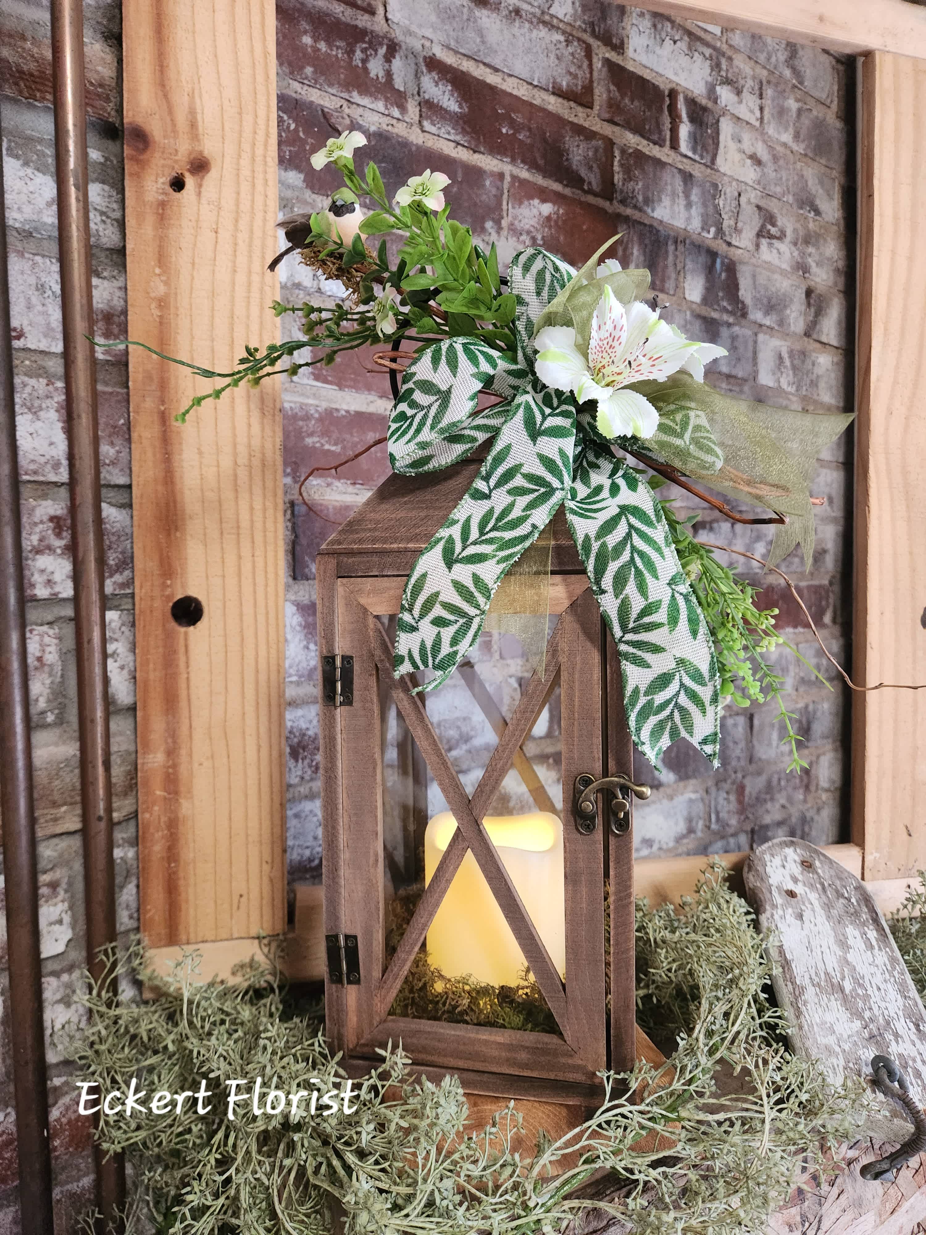 Eckert Florist's Brown Open Top Lantern *Our Local Delivery Only Eckert Florist's Brown Open Top Lantern *Our Local Delivery Only - This lantern arrives with a battery operated candle, designer ribbon, artificial decor, and our signature bird and twigs. Measures approx. bottom 5.5" square x 15" tall *Shape of lantern, artificial decor, and ribbon may vary. Our Local Delivery Only