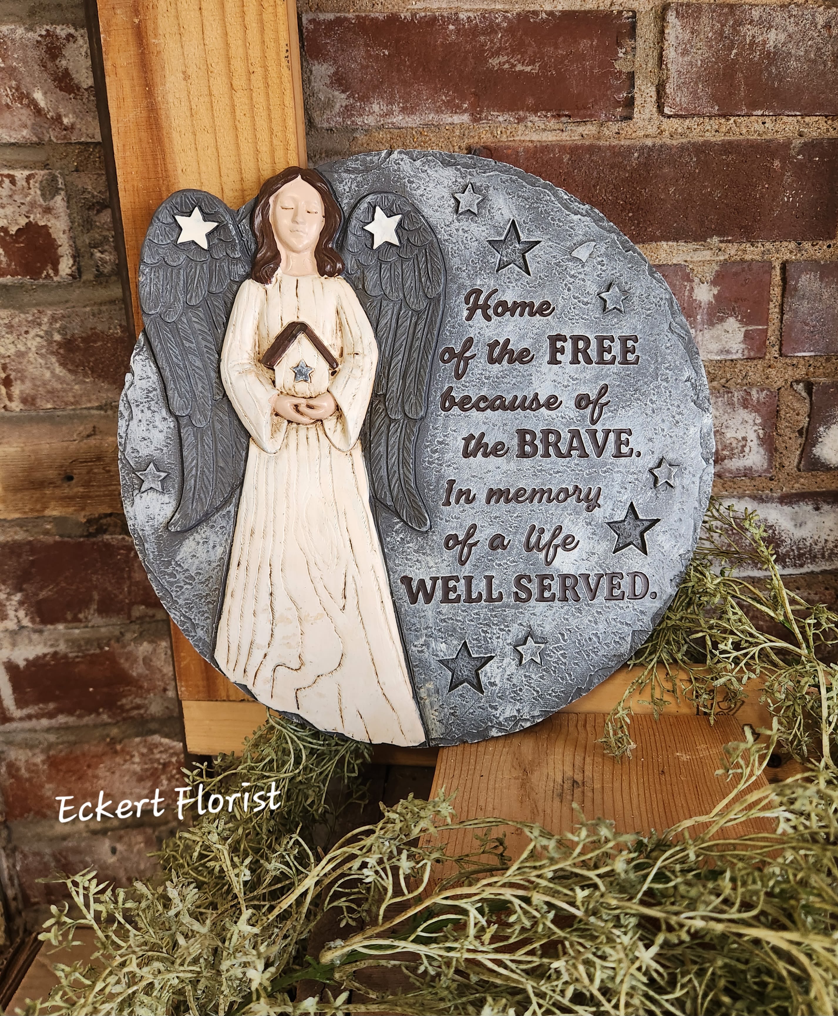 Eckert Florist's "Home Of The Free..." Memorial Stone *Our Local Delivery Only Eckert Florist's "Home Of The Free..." Memorial Stone *Our Local Delivery Only - Round resin stone measures approx. 10.5" Diameter This nice memorial keepsake may be sent to a funeral/memorial service or home. Can be added to a green plant or fresh arrangement. See Deluxe or Premium upgrades. Sentiment: "Home of the Free because of the Brave. In memory of a life Well Served" *See Add-on Section for Display Easel *LOCAL DELIVERY ONLY