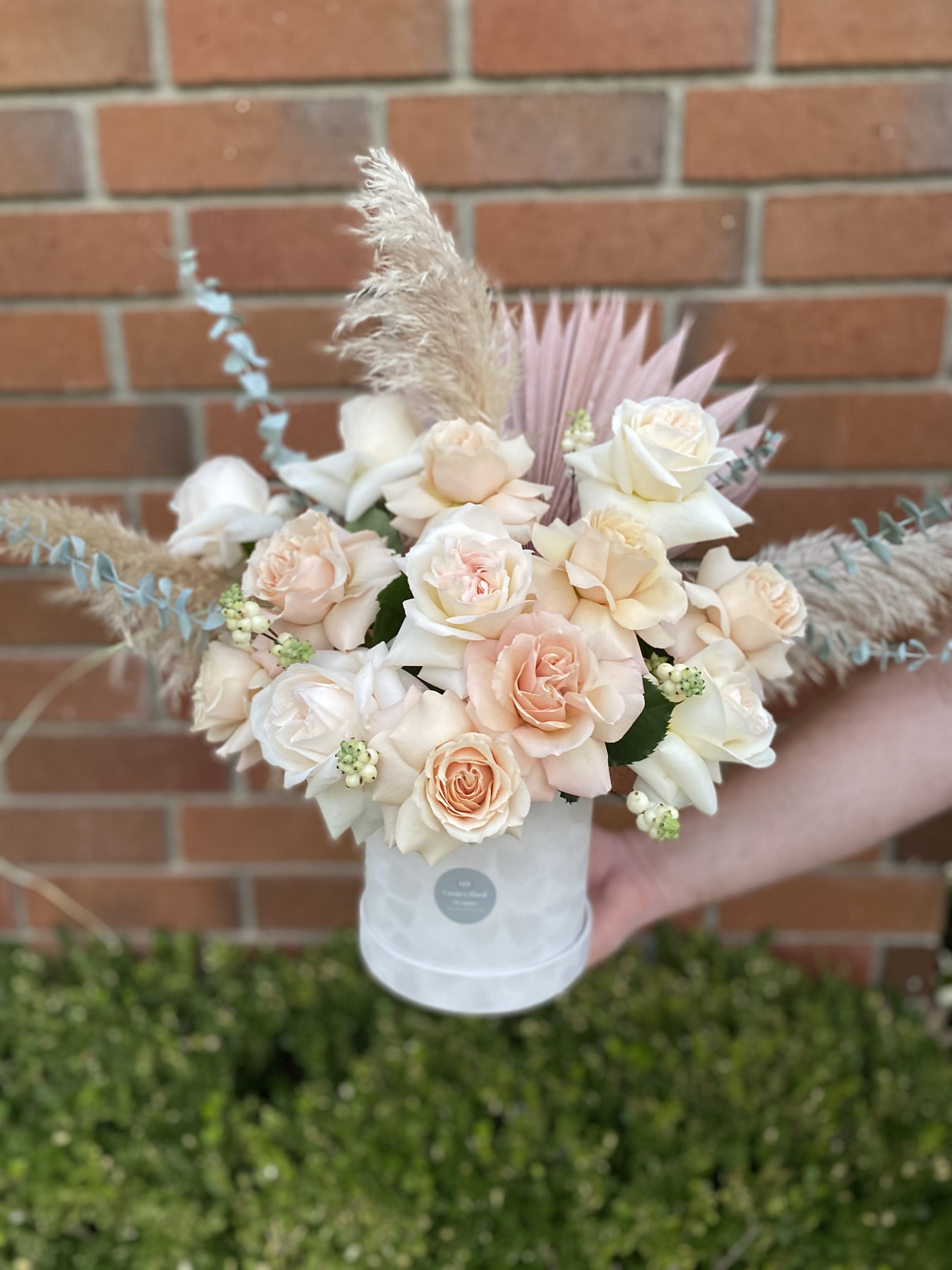 Sun Kissed Blush - A beautiful design that has soft blush and sandy colors to brighten anyone's day. A mixture of fresh and preserved flowers that give this design a contrast of textures. The arrangement comes in a beautiful, velvet, off-white hat box.