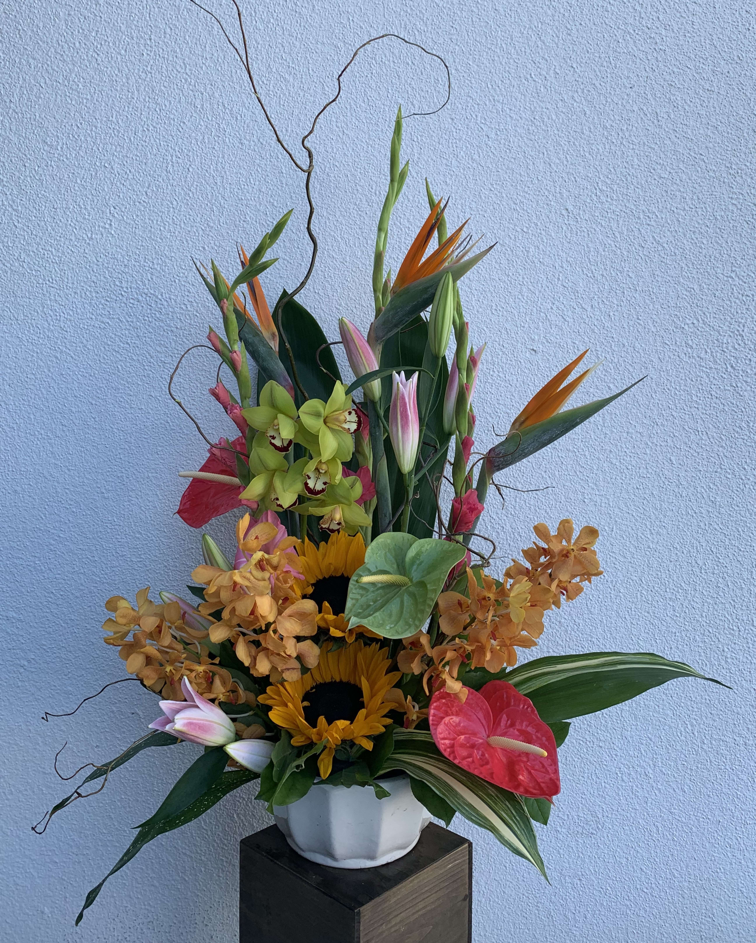 Exotic Oasis - This beautiful display of flowers is sure to WOW.  This one of a kind arrangement includes, birds of paradise, dendrobium and mokara orchids, anteriums, sunflowers and lilies. We need advance notice on this arrangement to ensure tropical flowers are available