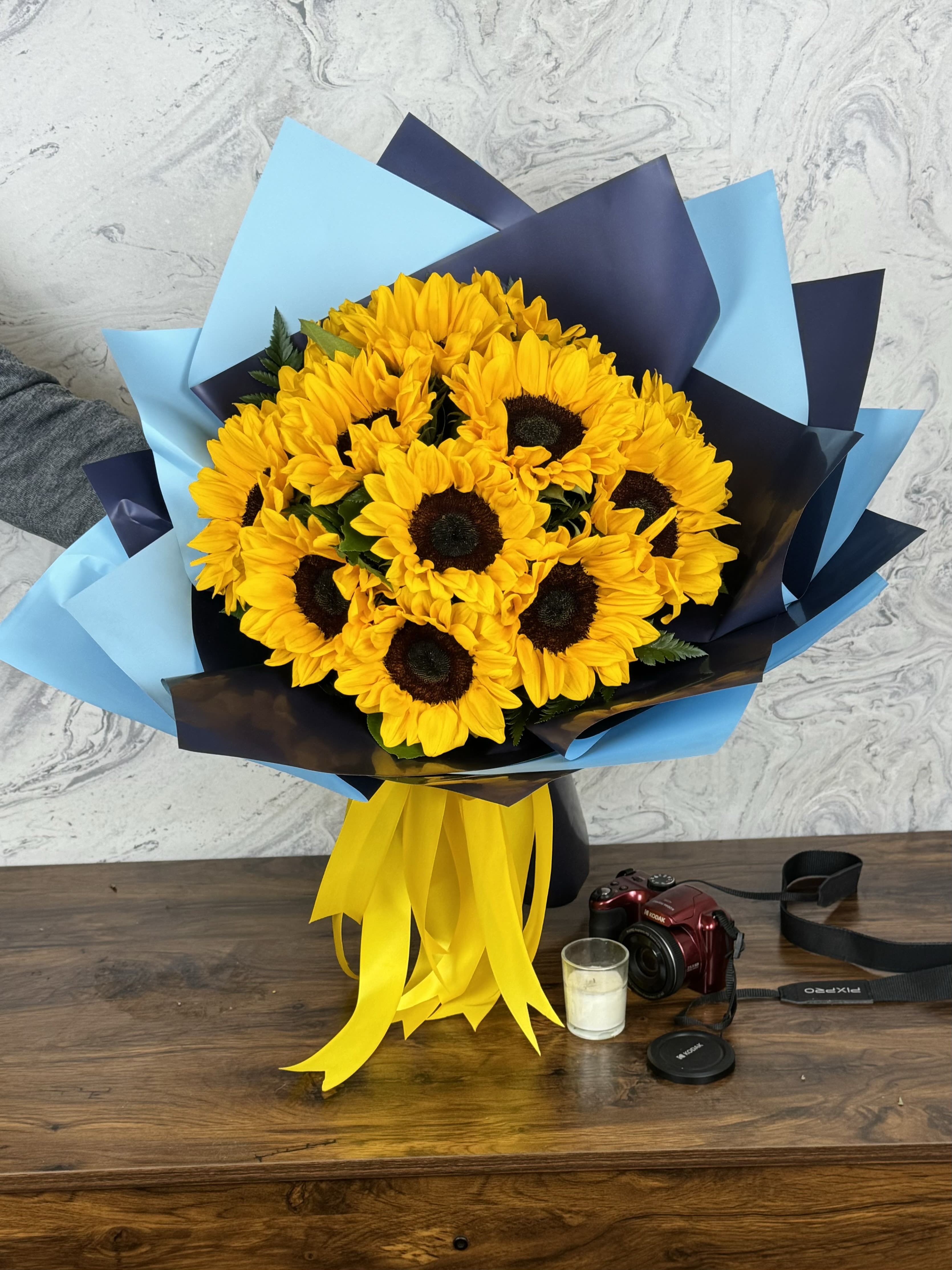 Sunflower Serenity - **Sunflower Serenity**: Discover the vibrant beauty of our handcrafted sunflower arrangements, where each stem is thoughtfully wrapped in elegant, water-proof paper. Our stunning designs, featuring rich navy blue or dark brown accents, add a touch of warmth and sophistication to any occasion. Perfect for celebrations, gifts, or simply brightening your space, our arrangements bring the joy of sunflowers to life. Experience the serenity of nature with every bloom at Sunflower Serenity.