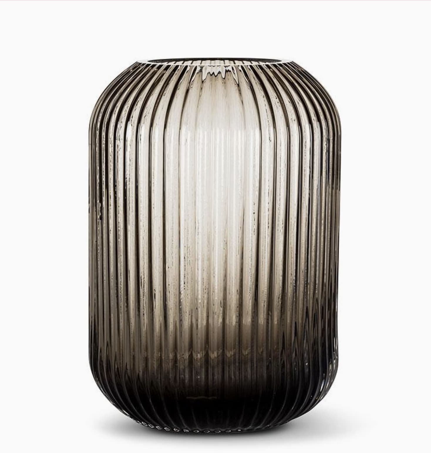 Medium Ridge Capsule Vase - GRAY - Enhance your space with the Medium Ridge Capsule Vase, a versatile and stylish addition that complements both floral arrangements and candle displays. Crafted from brown tinted glass, this vase features a distinctive capsule shape and is accented with a textured ribbed pattern that beautifully reflects and diffuses light, creating a warm, inviting ambiance. Measuring 6.5 x 6.5 x 9 inches, it's perfectly sized for use on tables, shelves, or mantels. Ideal for adding a touch of sophistication to any decor, this vase is a must-have for anyone looking to create a captivating visual experience in their home or office. Available at Chartreuse by Roje.
