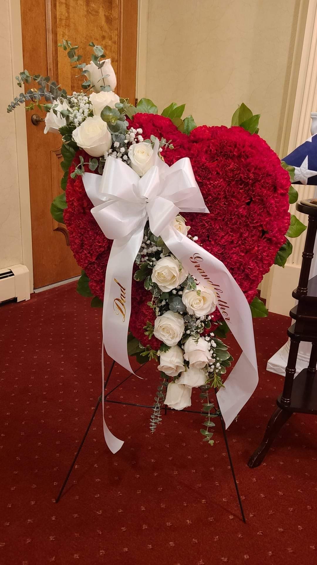 Heart Standing Spray Heart Standing Spray - A solid carnation heart with a spray of white roses enhance this sympathy tribute. This item can be designed in any color.