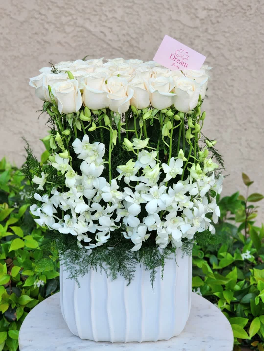 Sweet Angel  - Enhance your decor with a tall ceramic white vase, featuring white roses, white orchids, and lush ferns. Perfect for home decor, weddings, and events, this elegant arrangement adds sophistication and timeless beauty to any space.