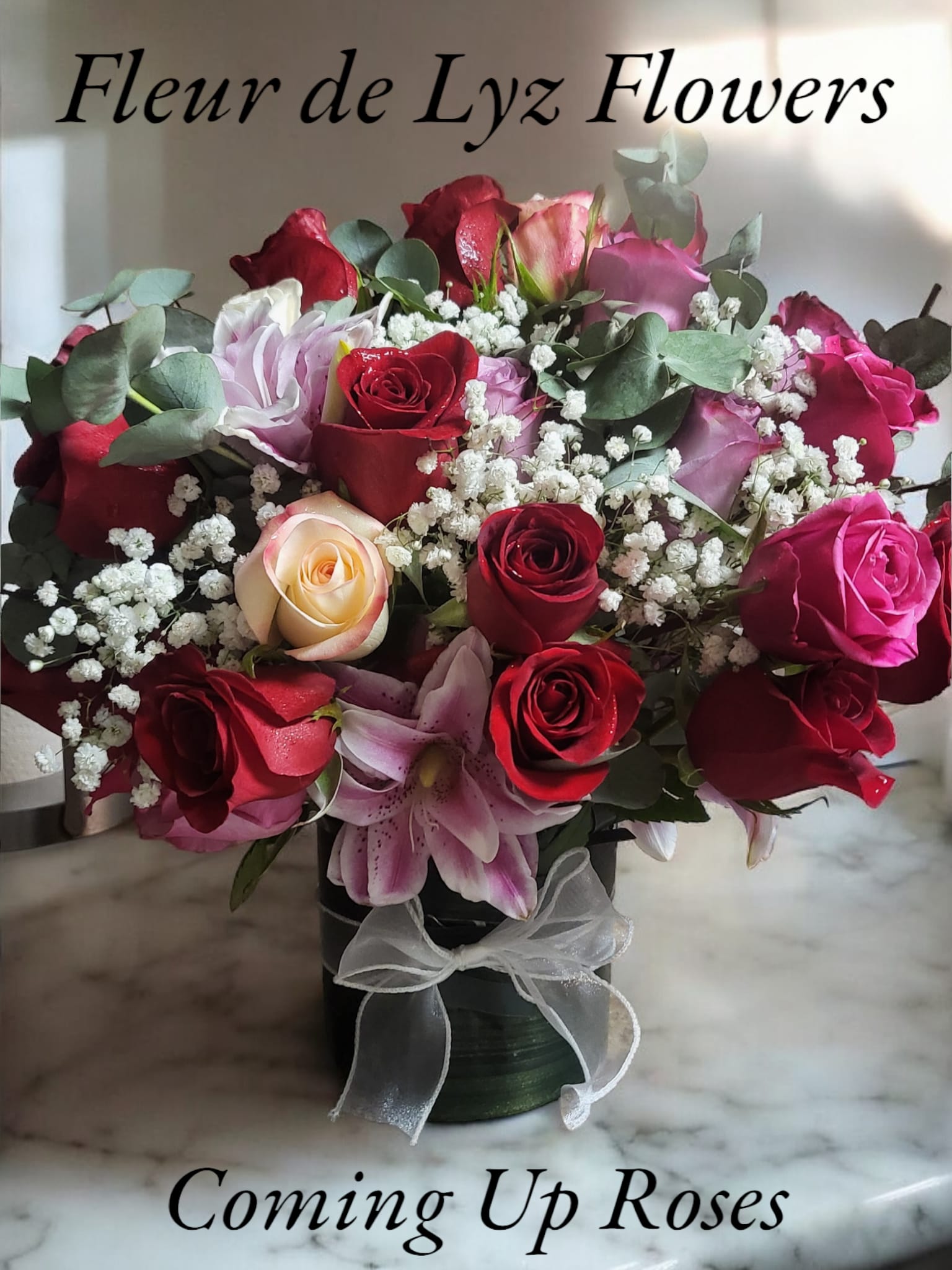 Coming up Roses Coming up Roses - A stunning bouquet of 24 roses in a variety of colors, Eucalyptus and Baby's breath and Asiatic Lilies designed in a glass vase and adorned with a white Organza bow