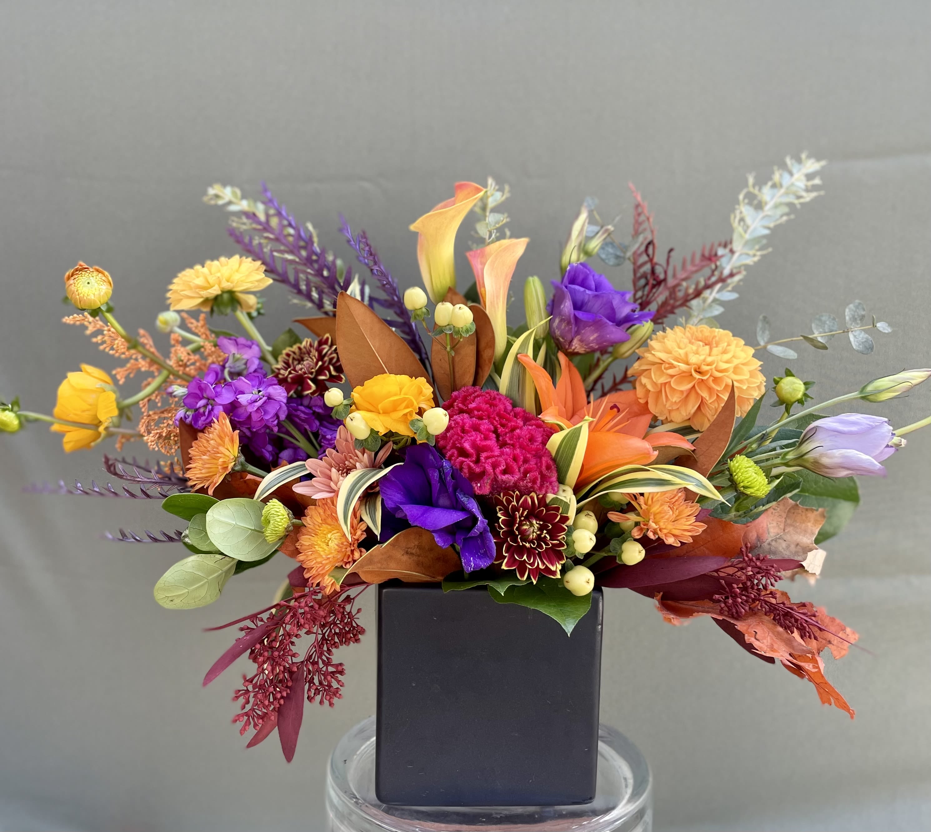 Sweet Cinnamon - This arrangement includes mini calla lilies, dahlias, lisianthus, lilies, ranunculus, stocks, and green foliage all beautiful arranged in ceramic black vase.