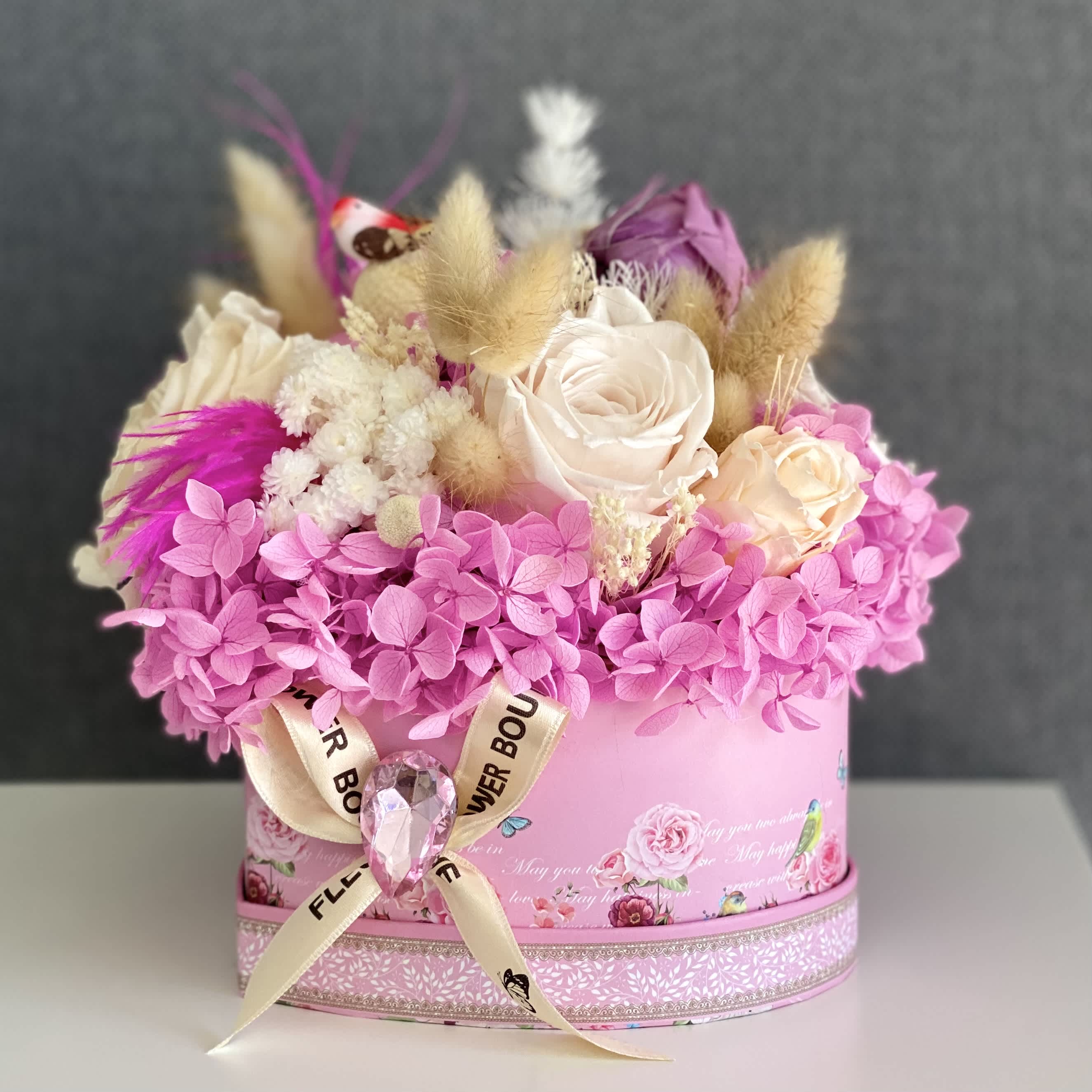 Rosy Heartfelt: Eternal Box Rosy Heartfelt: Eternal Box - Introducing the Rosy Heartfelt Eternity Box, a stunning expression of everlasting love and beauty. Embracing a charming heart-shaped design, this small flower box features an enchanting blend of pink preserved hydrangea, delicate mini preserved roses, and an assortment of carefully selected dried elements, all crafted to stand the test of time. Each element is meticulously arranged within the heart-shaped enclosure, creating a captivating and enduring arrangement that radiates love and elegance. Whether given as a heartfelt token of affection or displayed as a symbol of enduring love, the Rosy Heartfelt Eternity Box is a timeless masterpiece that captures the essence of romance and everlasting beauty.