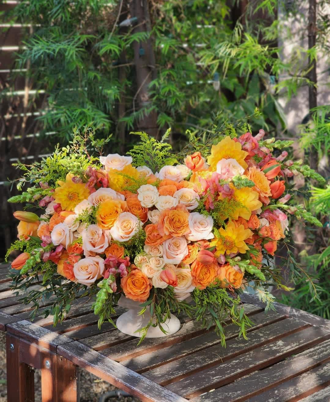 Pasadena Gardens  - The arrangement features vibrant oranges dahlias, soft peaches roses, and lush greens eucalyptus, creating a harmonious garden-style bouquet in a ceramic vase.   Recommended for: Thanksgiving,  Centerpiece, Love and Romance, , Anniversary, Flowers Gift, Birthday, Get Well Soon, Celebrations, Best Wishes, Thank You, Congratulations, Just Because, New Baby, Everyday, Gift Idea 