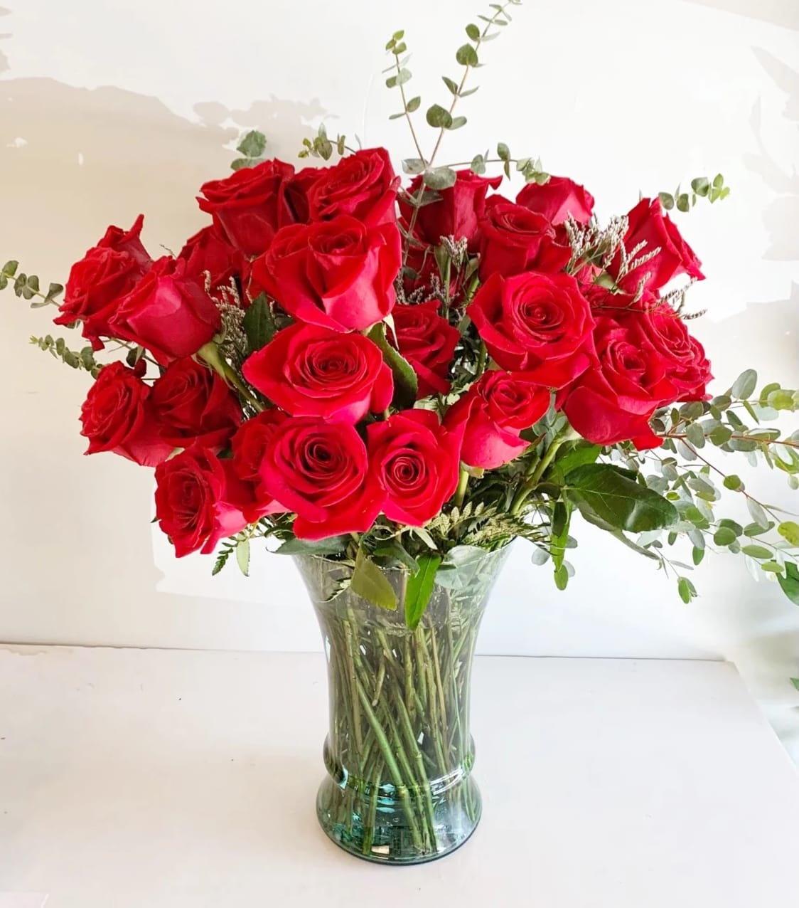 4 Dozen long stem red roses  - A lush arrangement of classic red roses in a tall clear vase, accented with beautiful greenery and fillers. *Pictured is 4 dozen  Standard: 4 dozen (as pictured) Deluxe: 5 dozen