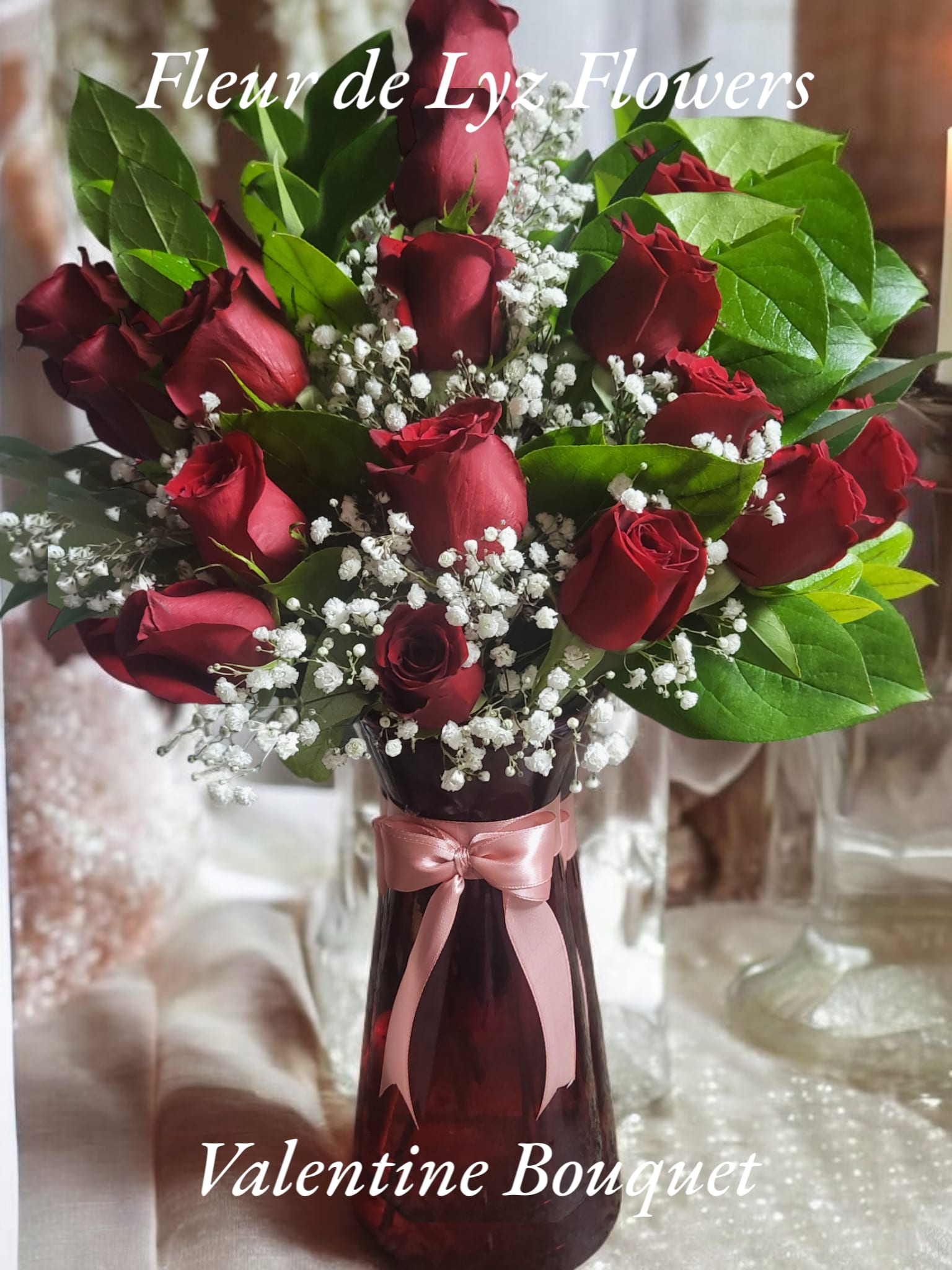 Valentine Bouquet Valentine Bouquet - A dozen red rose bouquet arrangement which includes Baby's breath designed in a red vase and accented with a pink bow. A Valentine's Day favorite.