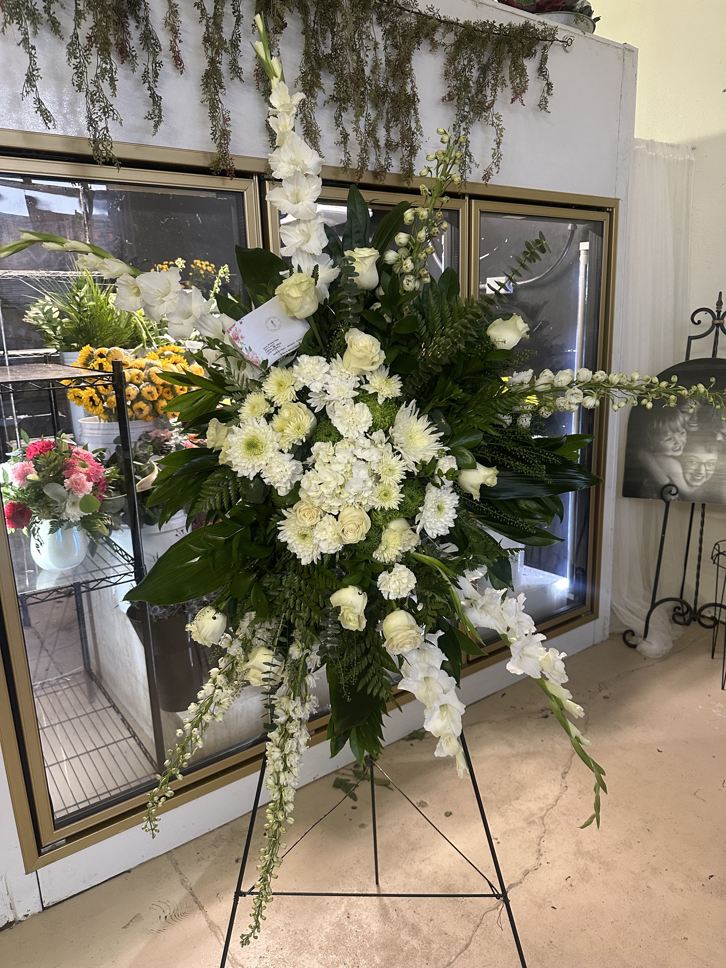 Designer's Choice Standing Spray - Our Designer's Choice Standing Spray is a breathtaking tribute, expertly crafted by our skilled florists to honor life's most significant moments. This elegant arrangement features a harmonious blend of seasonal flowers and lush greenery, thoughtfully chosen to create a stunning visual impact.  Whether for a memorial service, a celebration of life, or a special occasion, each standing spray is uniquely designed to reflect the emotions and sentiments of the moment. With an array of colors and textures, the spray serves as a heartfelt expression of love and remembrance.   Let our designers create a beautiful, customized standing spray that captures the essence of your message and pays tribute to cherished memories.  