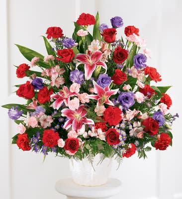Eternal Solace Arrangement Eternal Solace Arrangement - An abundance of Stargazer lilies, red roses and carnations, purple lisianthus and monte casino fill a deep mache basket. An elegant expression of sympathy. Approximately 29H" X 29W".