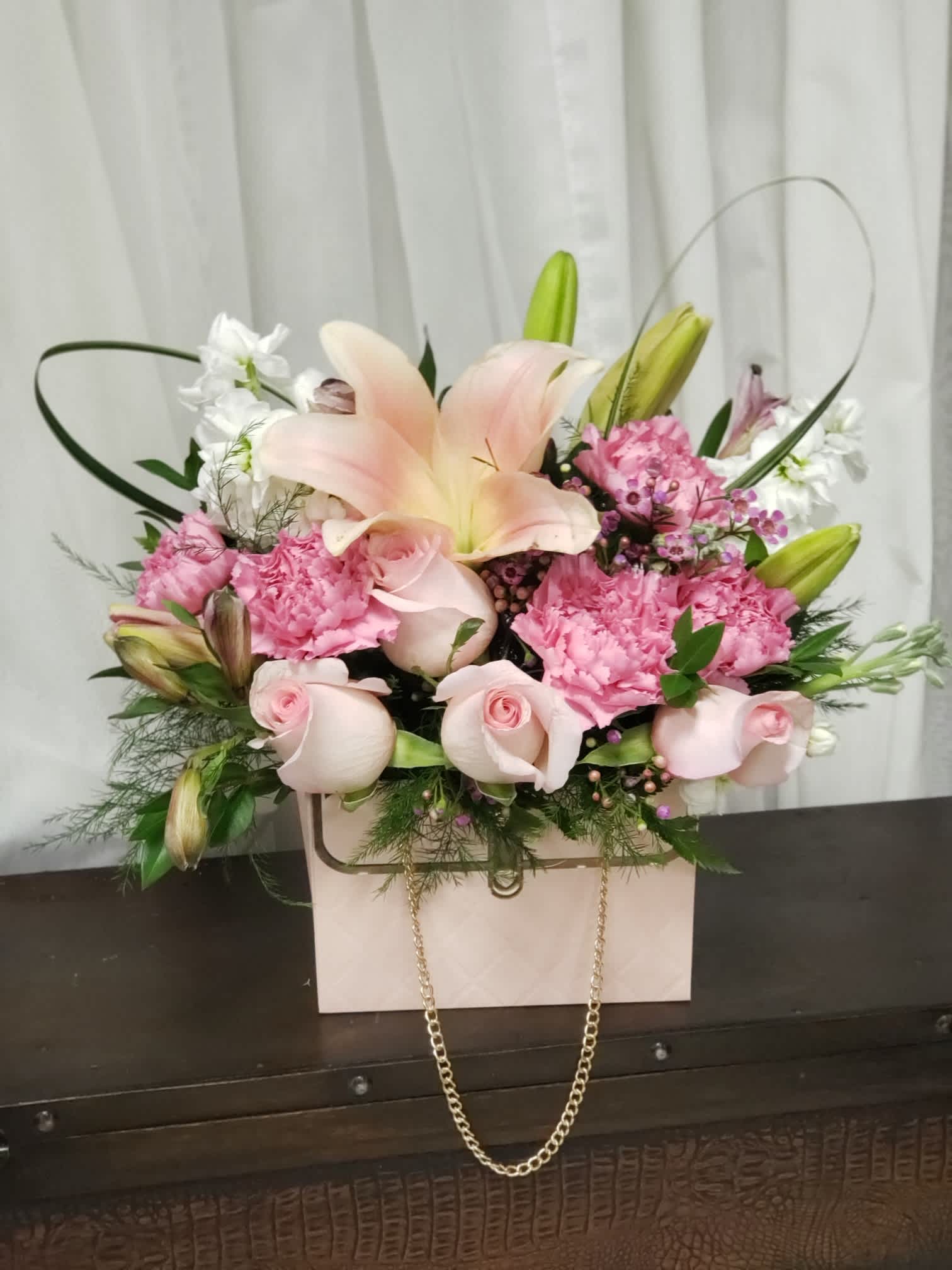 Blushing Bouquet - This Valentine's Day arrangement features a charming mix of delicate pink blooms fashioned into the a purse. The ensemble includes soft pink roses, dainty carnations, and subtle accents of greenery, creating a whimsical and romantic expression of love. The &quot;Blushing Bouquet&quot; is a stylish and heartfelt gift for your special someone.