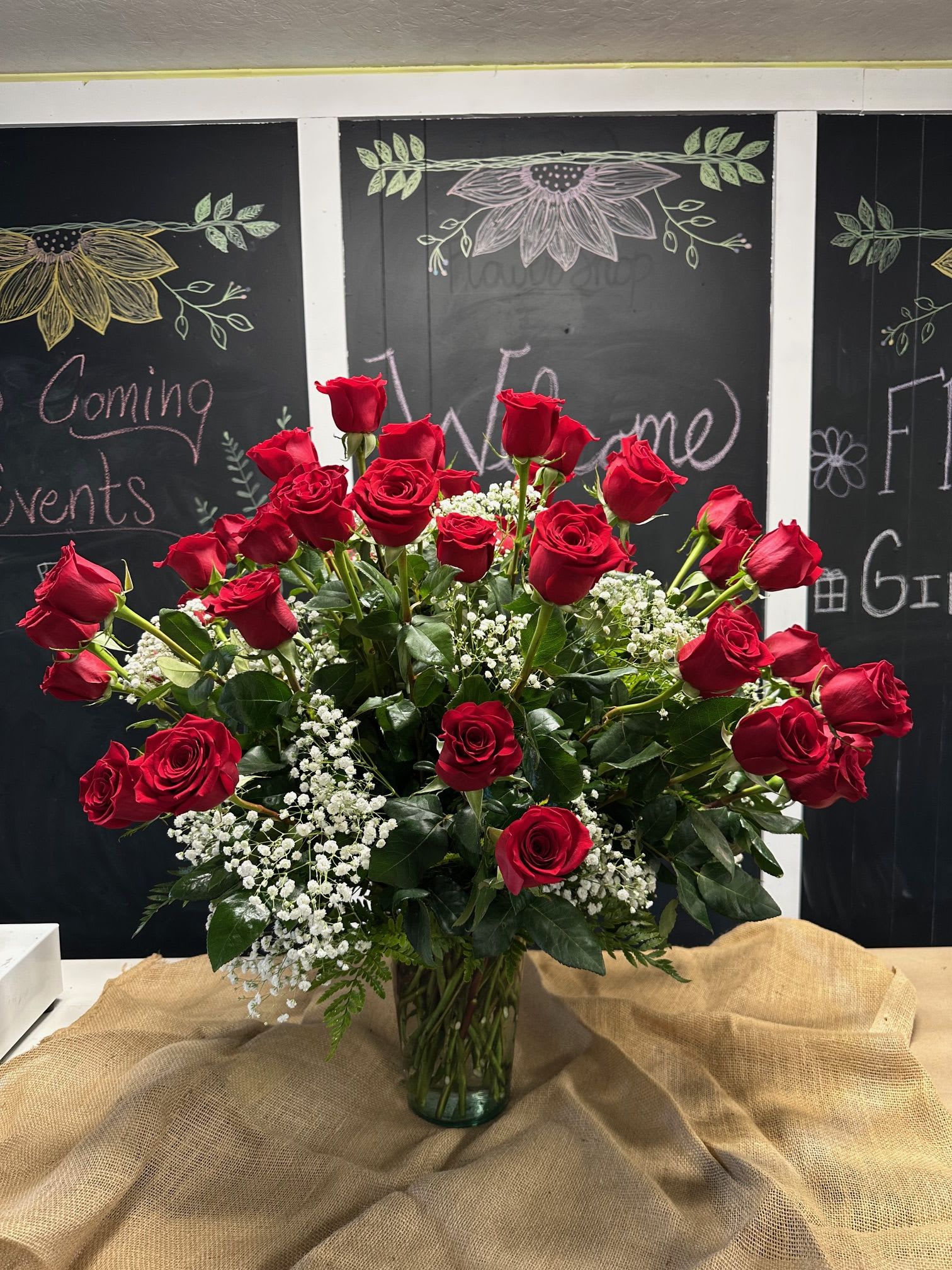 Roses with the Most - This grand arrangement of long stem red roses can be so versatile! Shown are 50 roses but we can easily add or take away a few to give the EXACT number needed for the occasion at hand. Filled traditionally with baby's breath and greens leaves the roses in the spotlight, where they should be. 