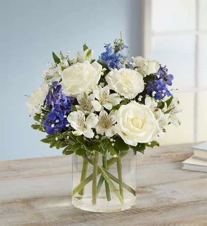 Winter wish - Inspired by winter’s cool blue &amp; white landscape, our delightful arrangement delivers warm wishes to the people you love. Hand-designed with a lush gathering of blooms, evergreens and rustic touches, it’s a thoughtful sentiment filled with the season’s natural beauty.  All-around arrangement with white roses, carnations and Peruvian lilies (alstroemeria); blue delphinium; accented with baby’s breath, seeded eucalyptus, assorted Christmas greenery and pinecones Artistically designed in a clear glass cylinder vase Large arrangement measures approximately 15&quot;H x 13&quot;W Medium arrangement measures approximately 13&quot;H x 12&quot;W Small arrangement measures approximately 12&quot;H x 9&quot;W Our florists hand-design each arrangement, so colors, varieties and container may vary due to local availability To ensure lasting beauty, Peruvian lilies may arrive in bud form and will fully bloom over the next few days