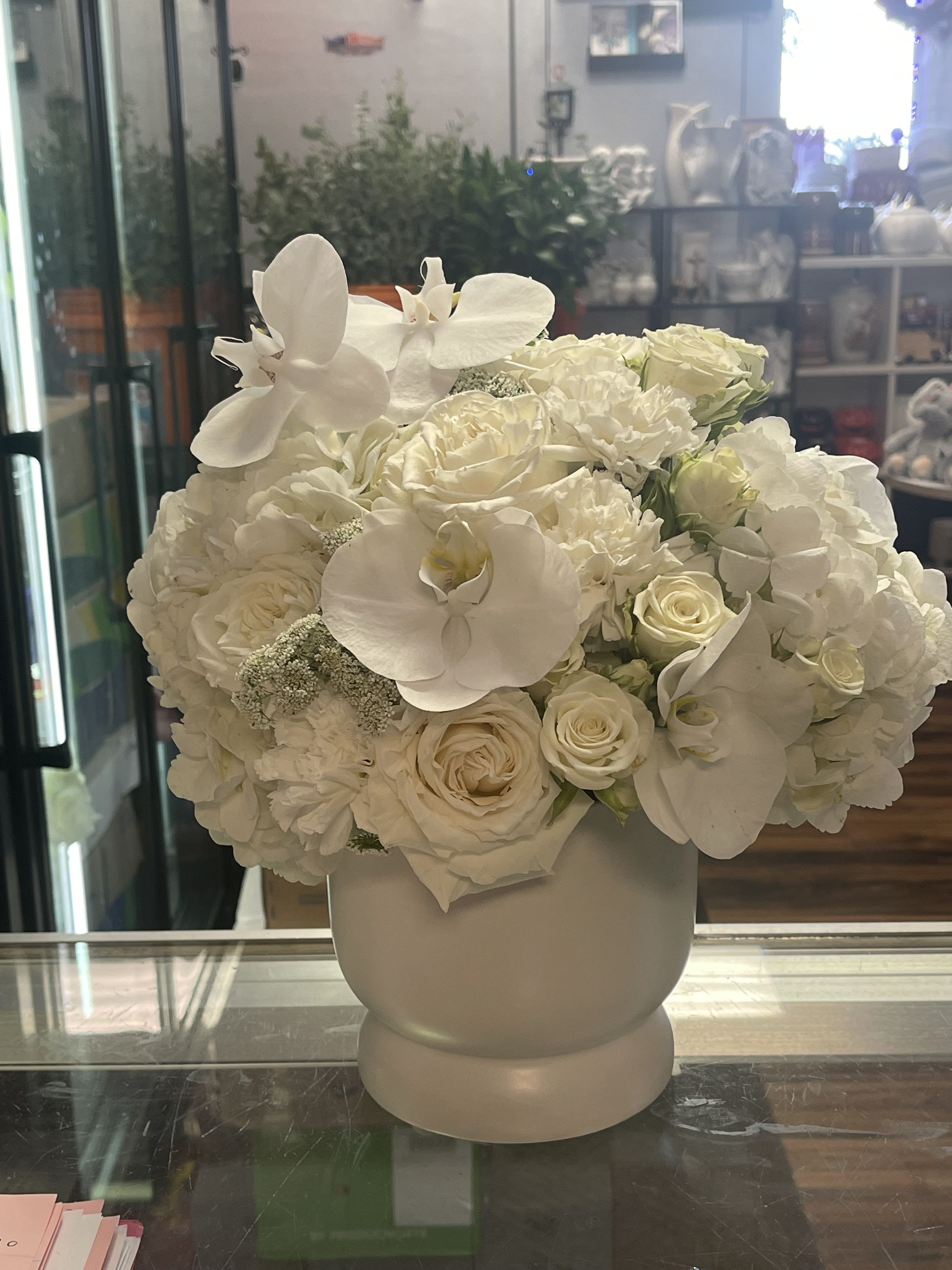 The Simply elegante all white floral The Simply elegante all white floral - This beautiful floral has a variety of white flowers such as, hydrangeas, white roses, orchids and spray roses in a white ceramic vase