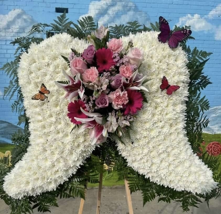 Wings #1 Wings #1 - Pay your loved one a beautiful tribute with this standing arrangement in form of wings. Made with roses, lily’s, gerbera daisies, carnations, alstroemerias, wax, cushion pompons, and assorted greenery. Call us to make custom changes.