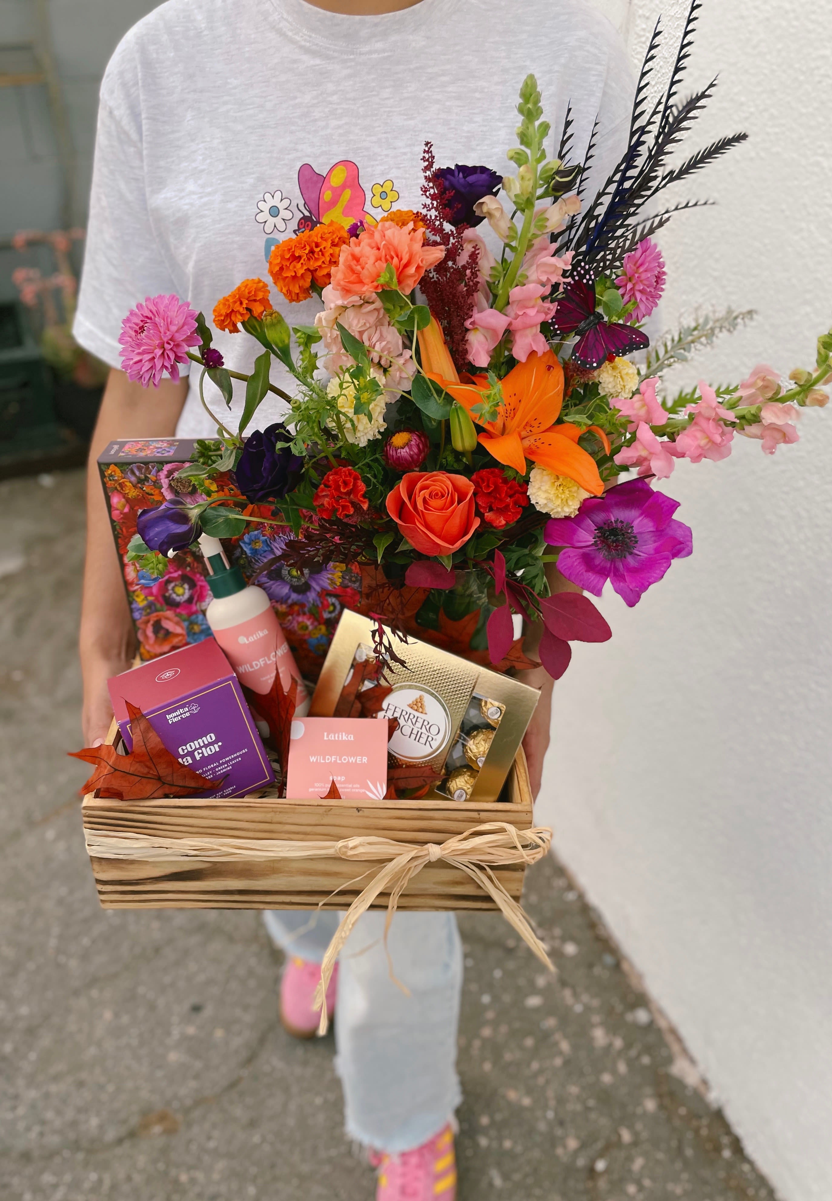 Floral Gratitude Crate - This charming gift box features a beautiful flower arrangement fill with a variety of fall flowers. It also includes an 8.5 oz Bonita Fierce Coconut soy candle, Latika hand and body cream, scented soap, Ferrero chocolates, a 1000 piece floral Puzzle and a small decorative pumpkin-perfect for a cozy fall self-care night!