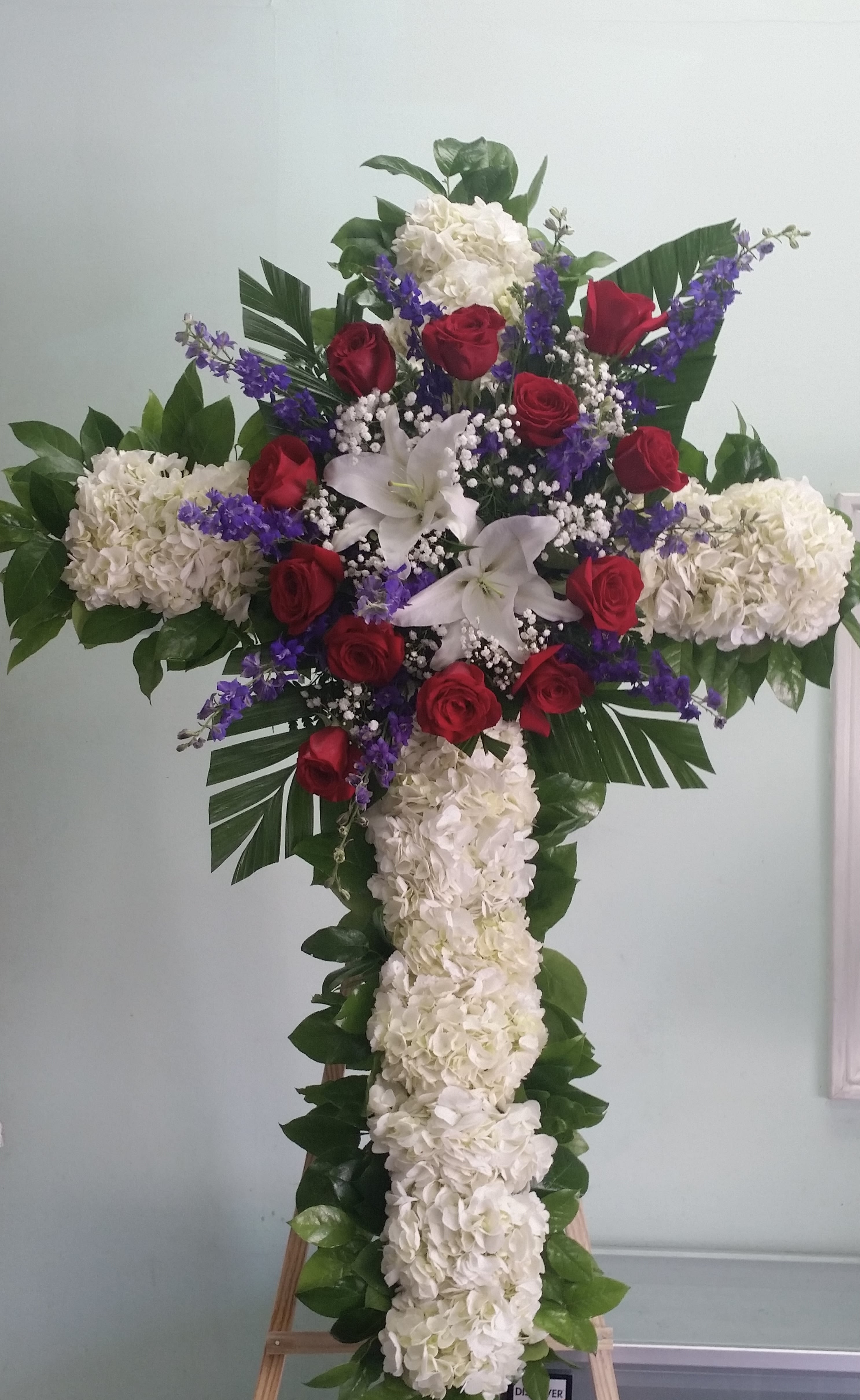 Blessing in Clouds Cross - Cross with white hydrangeas, red roses, white lilies, and purple larkspurs.