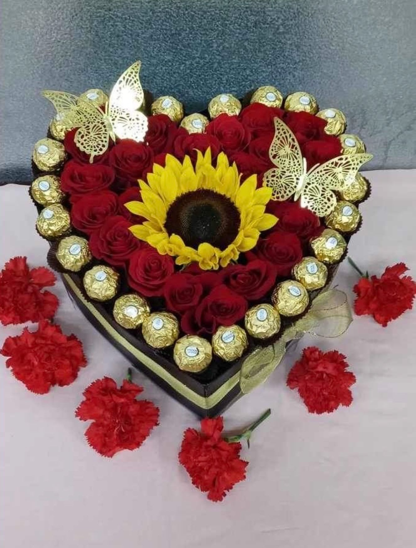 Heart Box 1 Heart Box 1 - 1 sunflower, 48-50 roses, 25 ferrero rocher chocolates, 2 decorative butterflies, in a black heart shaped box with a ribbon bow.