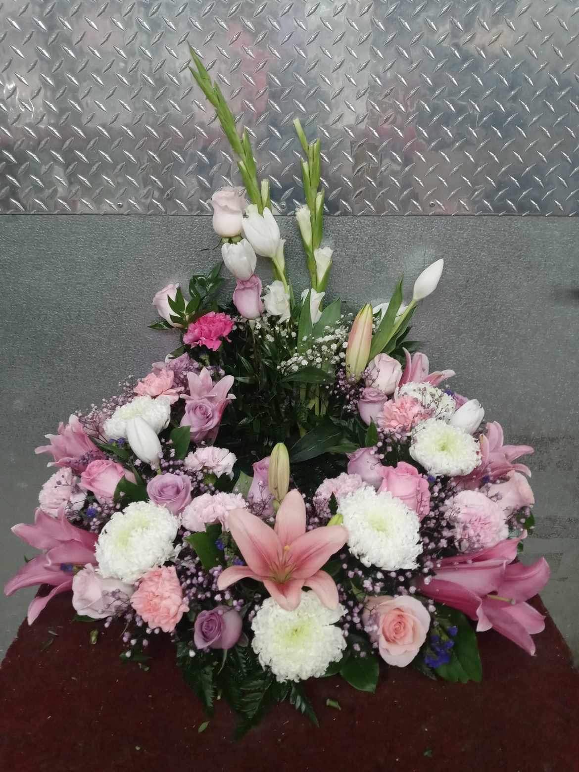 Urn #1 Urn #1 - Blushing pink floral arrangement that cradles the urn with roses, lily’s, gladiolus, carnations, tulips, china mums, baby breath, and assorted greenery.