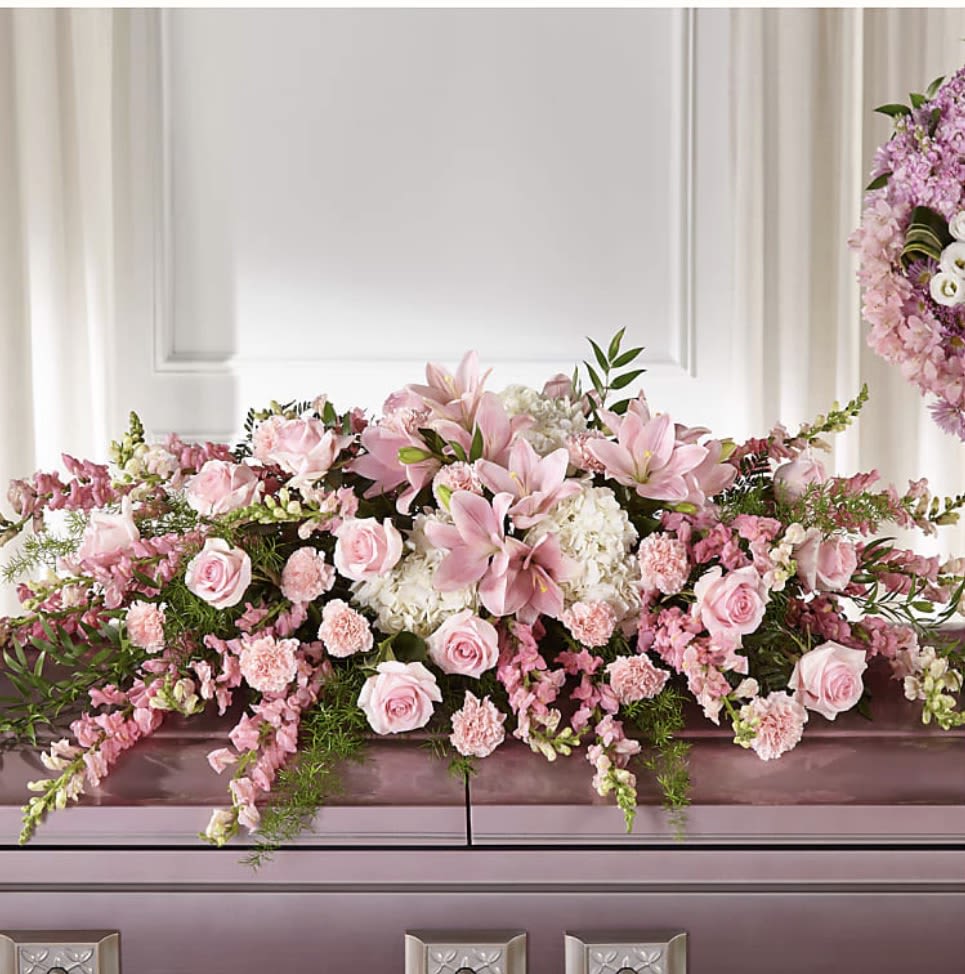 Life and Remembrance  - Pink flowers are comforting, dainty and add a touch of grace to your messages of sympathy. Our Life &amp; Remembrance Casket Spray beautifully celebrates the life of a loved one. Each arrangement is handcrafted by our talented designers with white hydrangea, pink lilies, roses and carnations.