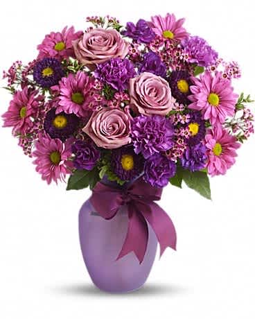 Love and Laughter - Know someone you love to make laugh? Someone you love to laugh with? Someone who could use a laugh? Someone who fits all of the above? Well, this beautiful arrangement has charms that extend way beyond its blossoms. Lavender roses and daisy spray chrysanthemums, purple carnations, miniature carnations, matsumoto asters and pink waxflower are delivered in a sweet lilac vase that's tied with a purple satin ribbon. Love, laugh and send it today!