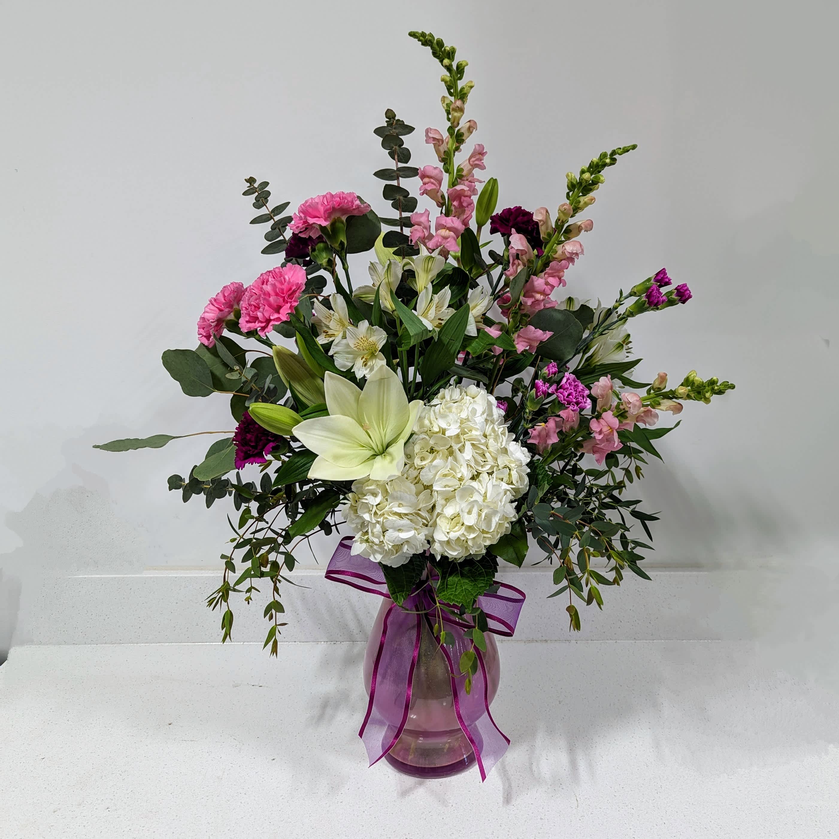Eternal Embrace Bouquet - Celebrate the everlasting bond of love this Mother's Day with our &quot;Eternal Embrace Bouquet.&quot; This exquisitely crafted floral arrangement is a symphony of color and fragrance, designed to convey deep appreciation and love for the most important woman in your life.  The bouquet features a stunning blend of lilies, carnations, hydrangeas, snapdragons, and alstroemeria, each chosen for their beauty and symbolic meanings. Lilies represent purity and devotion, while carnations are traditionally associated with a mother's undying love. Hydrangeas express heartfelt emotions and gratitude, snapdragons symbolize strength and grace, and alstroemeria, often referred to as the flower of friendship, adds a touch of enduring companionship and support.  Perfect for expressing your affection and gratitude, the &quot;Eternal Embrace Bouquet&quot; is an ideal gift for Mother's Day, reminding your mom, grandmother, or maternal figure just how much they are cherished. Accompanied by a personalized message, this bouquet will surely touch her heart and make this Mother's Day memorable.