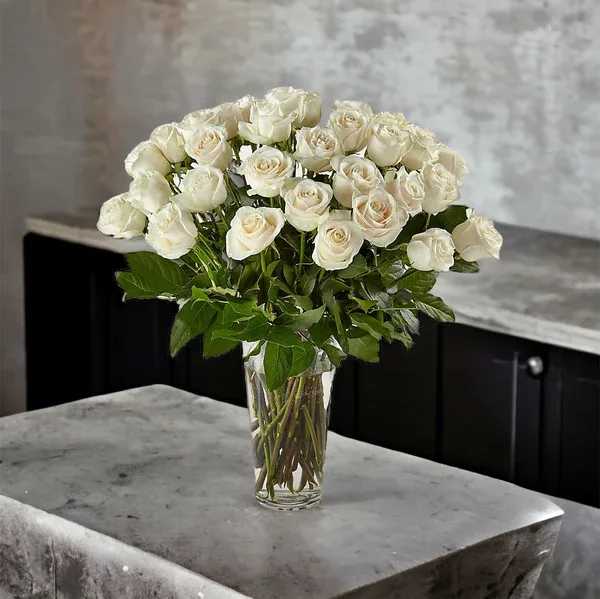 Luminous White Roses Bouquet Luminous White Roses Bouquet - White roses are elegant, luminous, and beautifully accent any room. With a gorgeous selection of crisp white roses among fresh greenery, this bouquet is perfect for birthdays, anniversaries, or as a way to say, "I'm thinking of you."  36 white roses with greens in a clear vase.  Please Note: The One Roses florists put love into every arrangement. Sometimes they have to substitute flower types, colors & containers to give you the freshest blooms available. Although your bouquet may vary from the photo shown, we anticipate your recipient will love it just as much!  Vase may be different from the image.