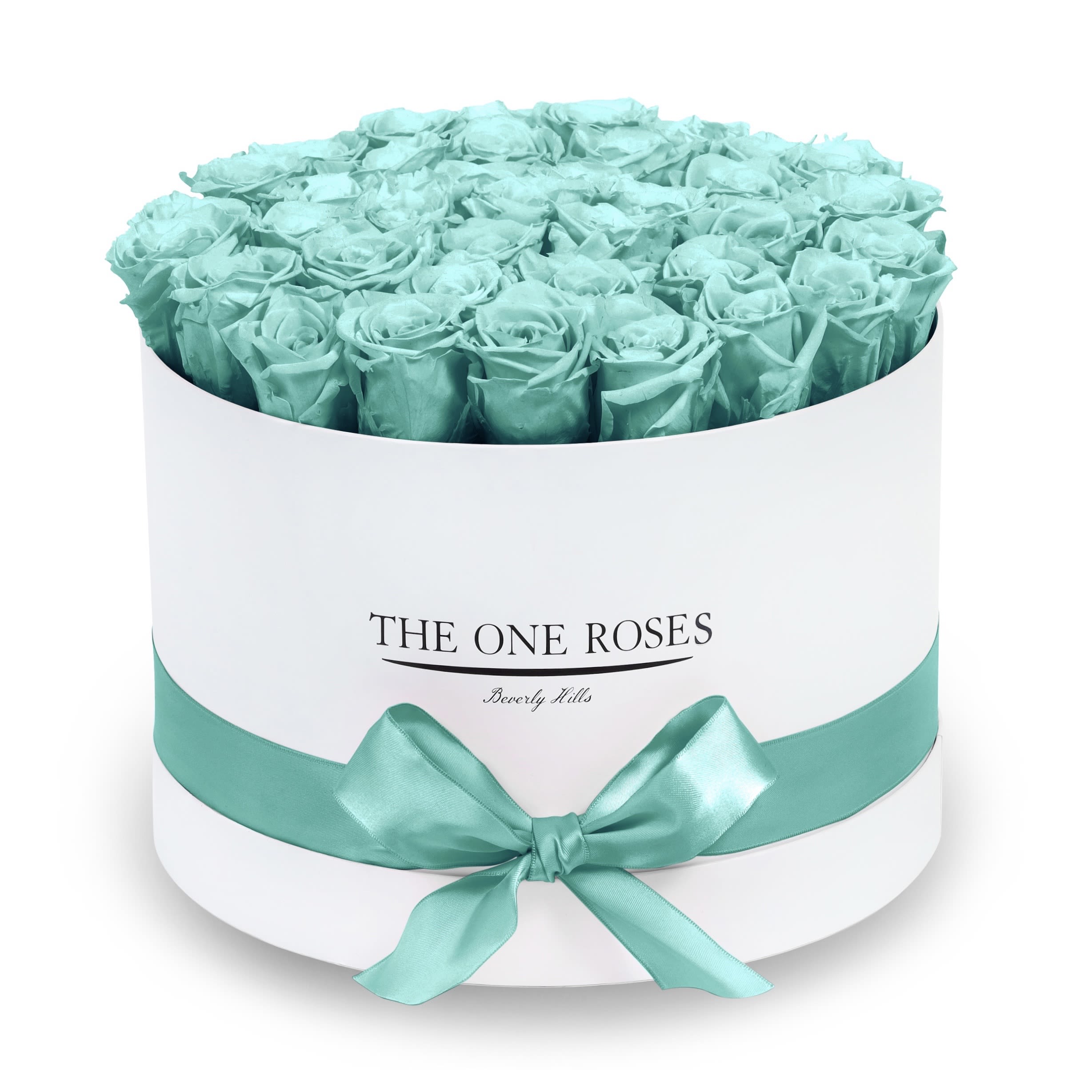 Round Flat | Premium White Box Teal Blue Round Flat | Premium White Box Teal Blue - The “Runway Round Collection”. consists of unique, real preserved roses in premium round handcrafted luxury soft touch box with a top. About 30-36 stems of The One long lasting (med size) preserved roses.  Durability: approx. 1-3 years.  Our roses, which are carefully sourced from the highest quality gardens in Ecuador, are made to represent the eternal yet ephemeral nature of Love itself. Our Roses are specially customized with essential oils to increase the fragrance.  Product Care: DO NOT Water the roses! AVOID direct exposure to sunlight. Keep the arrangement in a room-temperature environment. If dust collects after a few months, remove it lightly using a duster. DO NOT place anything onto the roses as they can crush and damage the roses. DO NOT remove the roses from the box; they are secure and happy there. DO NOT allow roses to have direct contact with light colored fabric or surfaces, as staining may occur. The lid is meant to stay on the side or bottom of the box. Be mindful when carrying the arrangement: it's a very delicate product!