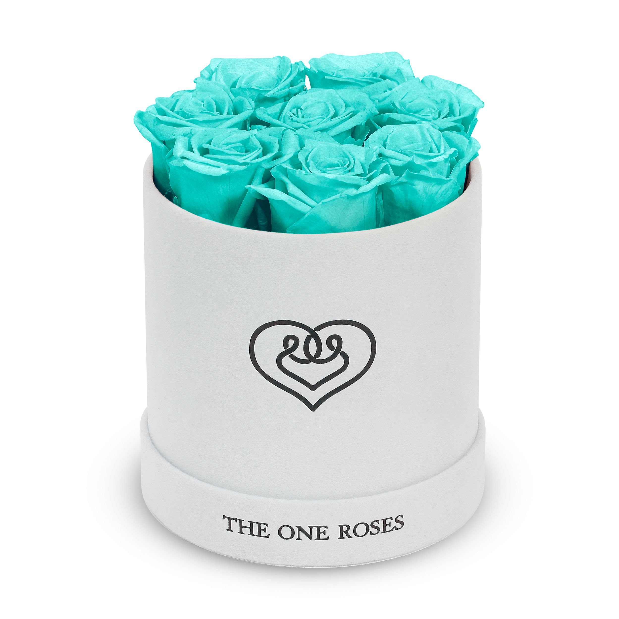 Suede Flat | Basic White Box Teal Blue Suede Flat | Basic White Box Teal Blue - Our White-Suede Basic Box with The One Eternity Roses comes in a luxury suede hand crafted box. About 8 stems of The One long lasting (med size) preserved real roses.  Durability: approx. 1-3 years.  Product Dimension: 6″ × 6″ / 8 ROSES  Our roses, which are carefully sourced from the highest quality gardens in Ecuador, are made to represent the eternal yet ephemeral nature of Love itself. Our Roses are specially customized with essential oils to increase the fragrance.  Product Care: DO NOT Water the roses! AVOID direct exposure to sunlight. Keep the arrangement in a room-temperature environment. If dust collects after a few months, remove it lightly using a duster. DO NOT place anything onto the roses as they can crush and damage the roses. DO NOT remove the roses from the box; they are secure and happy there. DO NOT allow roses to have direct contact with light colored fabric or surfaces, as staining may occur. The lid is meant to stay on the side or bottom of the box. Be mindful when carrying the arrangement: it's a very delicate product!