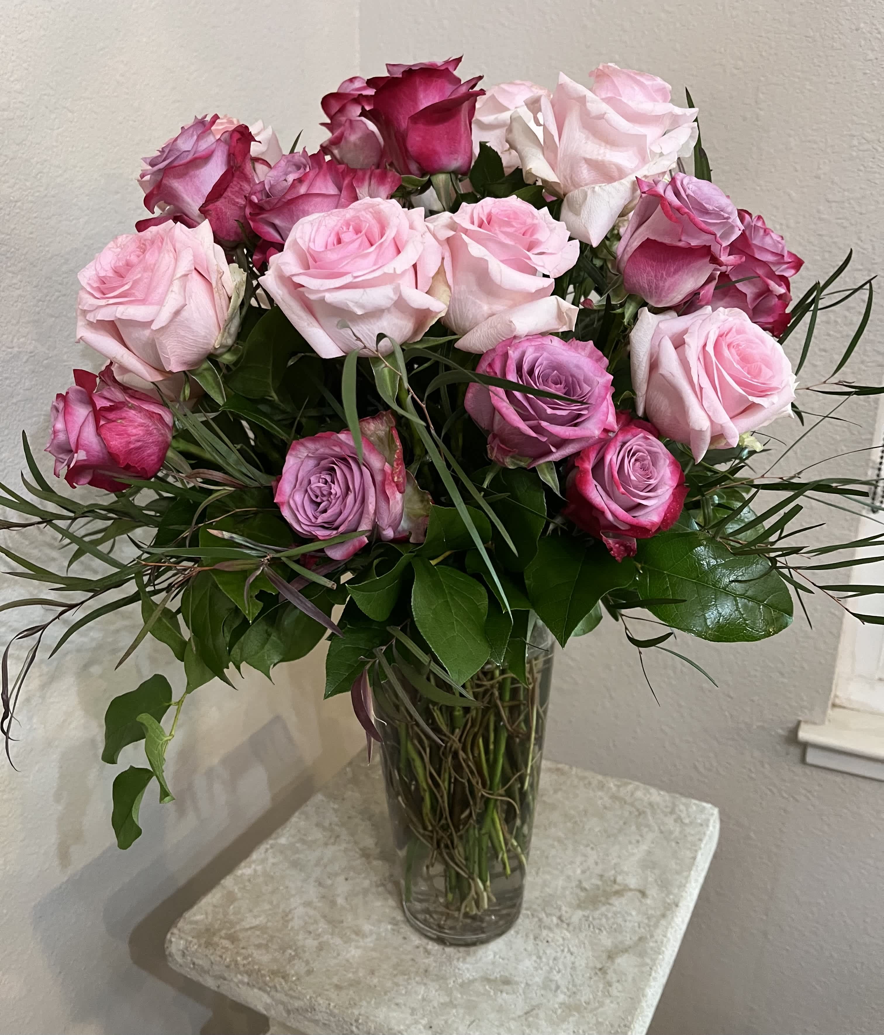 Two Dozen Roses in Lavender and Pink Two Dozen Roses in Lavender and Pink - A tall clear glass vase holds an arrangement of two dozen roses in shades of lavender and pink. Also available in other color combinations.