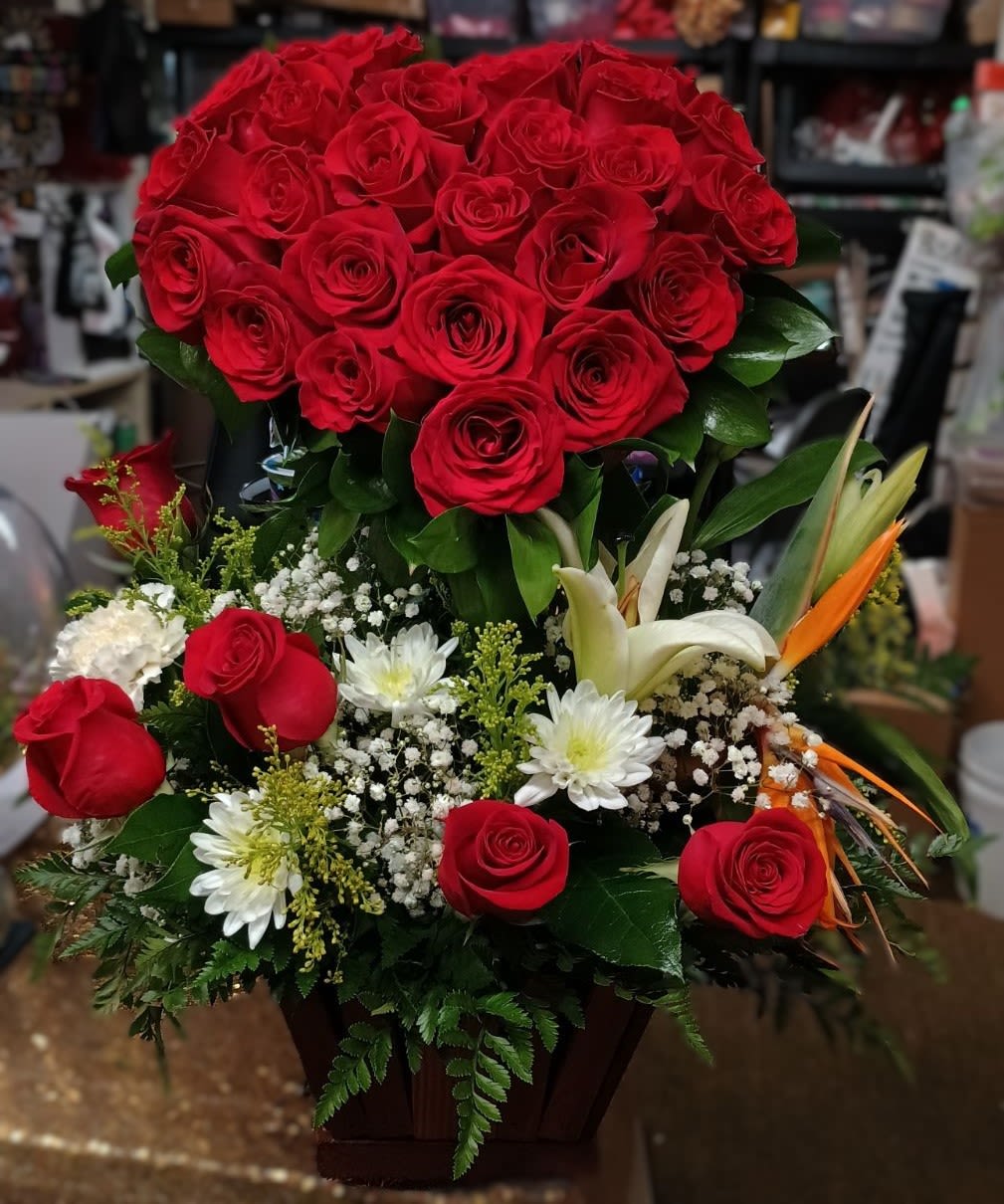 Small Wooden Heart Stand Small Wooden Heart Stand - An adoring whole rose heart arrangement in a wooden base with 1 lily stem, 1 birds of paradise stem , pompom cushions, solidalgo, 1-2 carnations, baby's breath, 4-5 roses, and assorted greenery.. Pet Safety Precautions: This arrangement may include flowers and foliage that are known to be toxic to pets. To keep them safe, be sure to keep this arrangement out of your pet's reach.