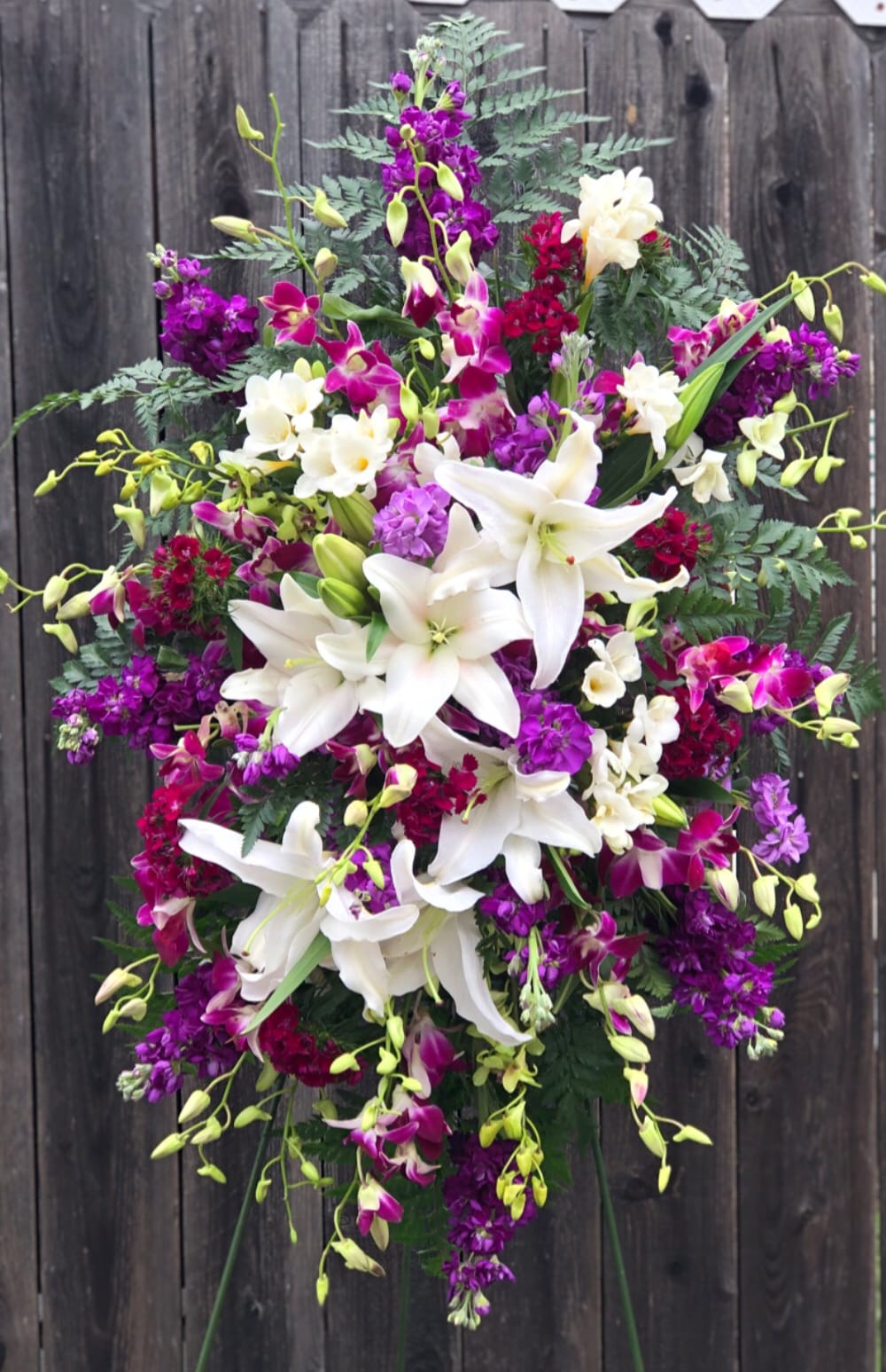 Everything Purple Standing Spray Bouquet - Standing spray bouquet for a woman who loved the shades of purple. Order this elegantly designed bouquet to send your sympathies and prayers to the departed family.   Approximately 34&quot; H x 24&quot; W