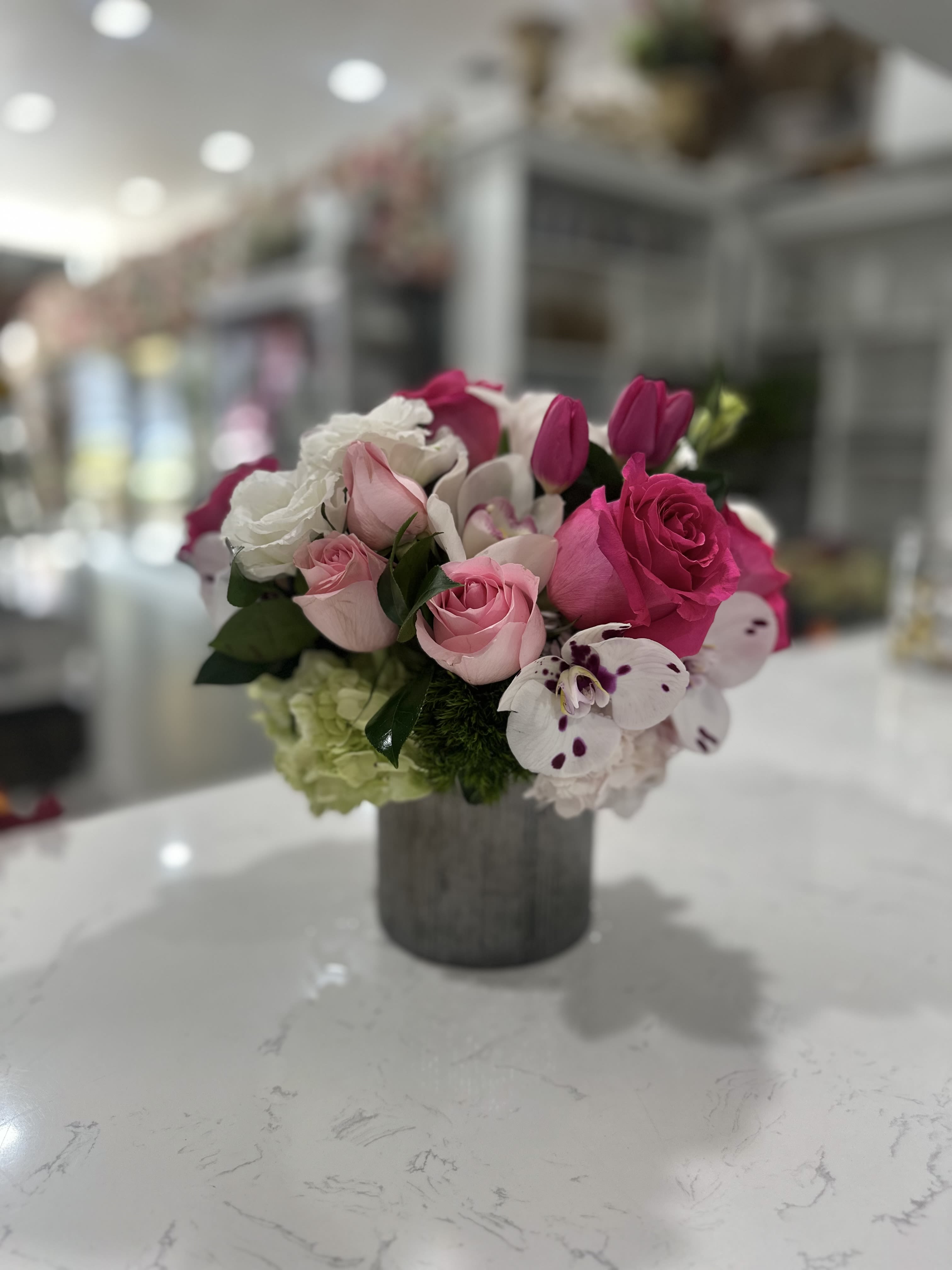Sweet Harmony - A delightful arrangement featuring a blend of pink and white roses, complemented by elegant tulips and unique spotted orchids. Soft green hydrangeas add depth and contrast, making this arrangement both romantic and cheerful, perfect for bringing warmth and elegance to any space.