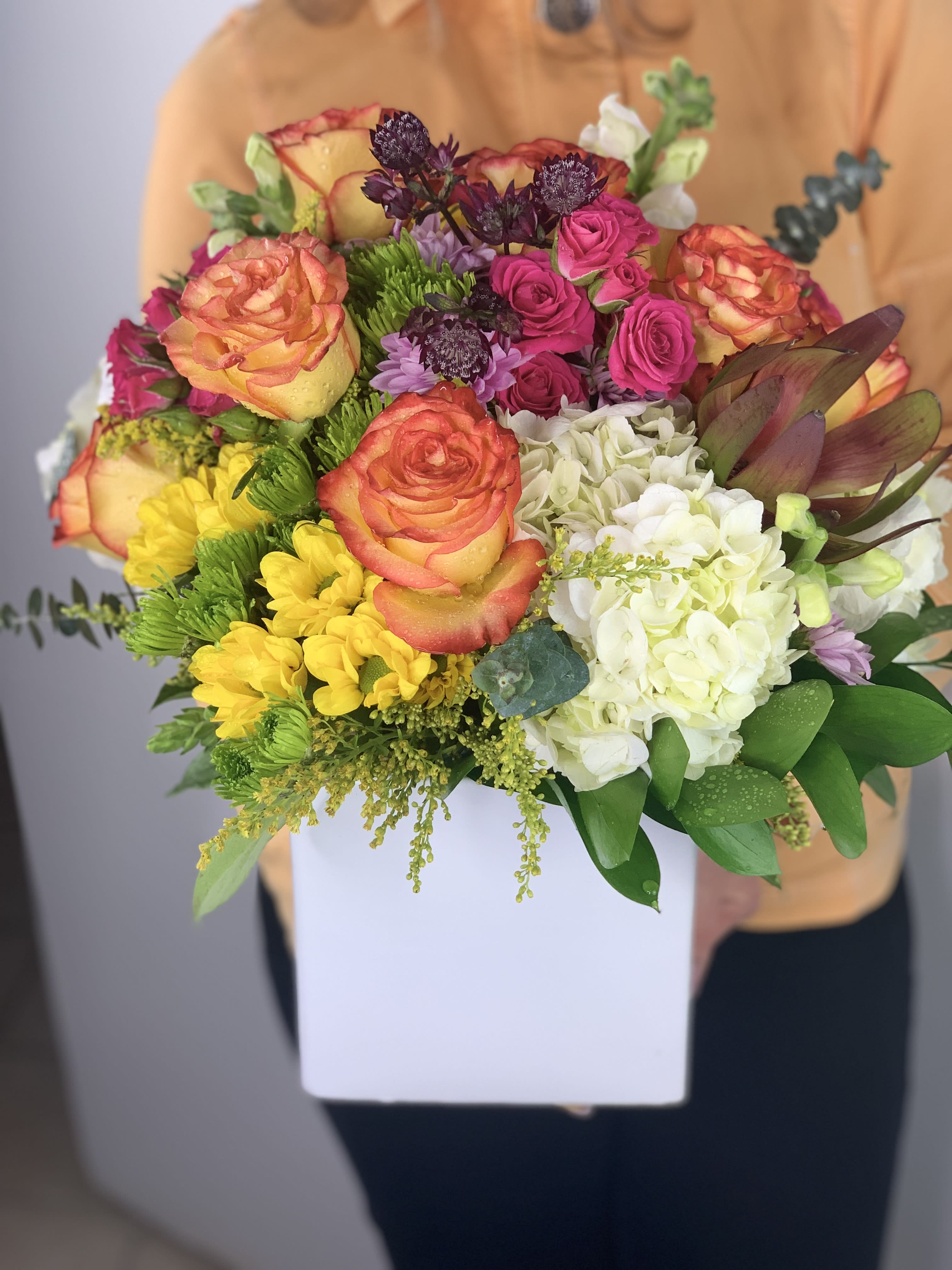 Flower Delight  - This arrangement is just beautiful with seasonal flowers and the freshest blooms arranged in a cube vessel. Size is medium and large. Colors and flowers are upon availability.  In some instances, our photo may represent an overall theme or look and include a one-of-a-kind vase which cannot be exactly replicated.  Although the actual bouquet may not precisely match the photo, its temperament will. Occasionally, substitutions of flowers and/or containers happen due to weather, seasonality and market conditions which may affect availability. If this is the case with the gift you’ve selected, we will ensure that the style, theme and color scheme of your arrangement is preserved and will only substitute items of equal value or higher value. 