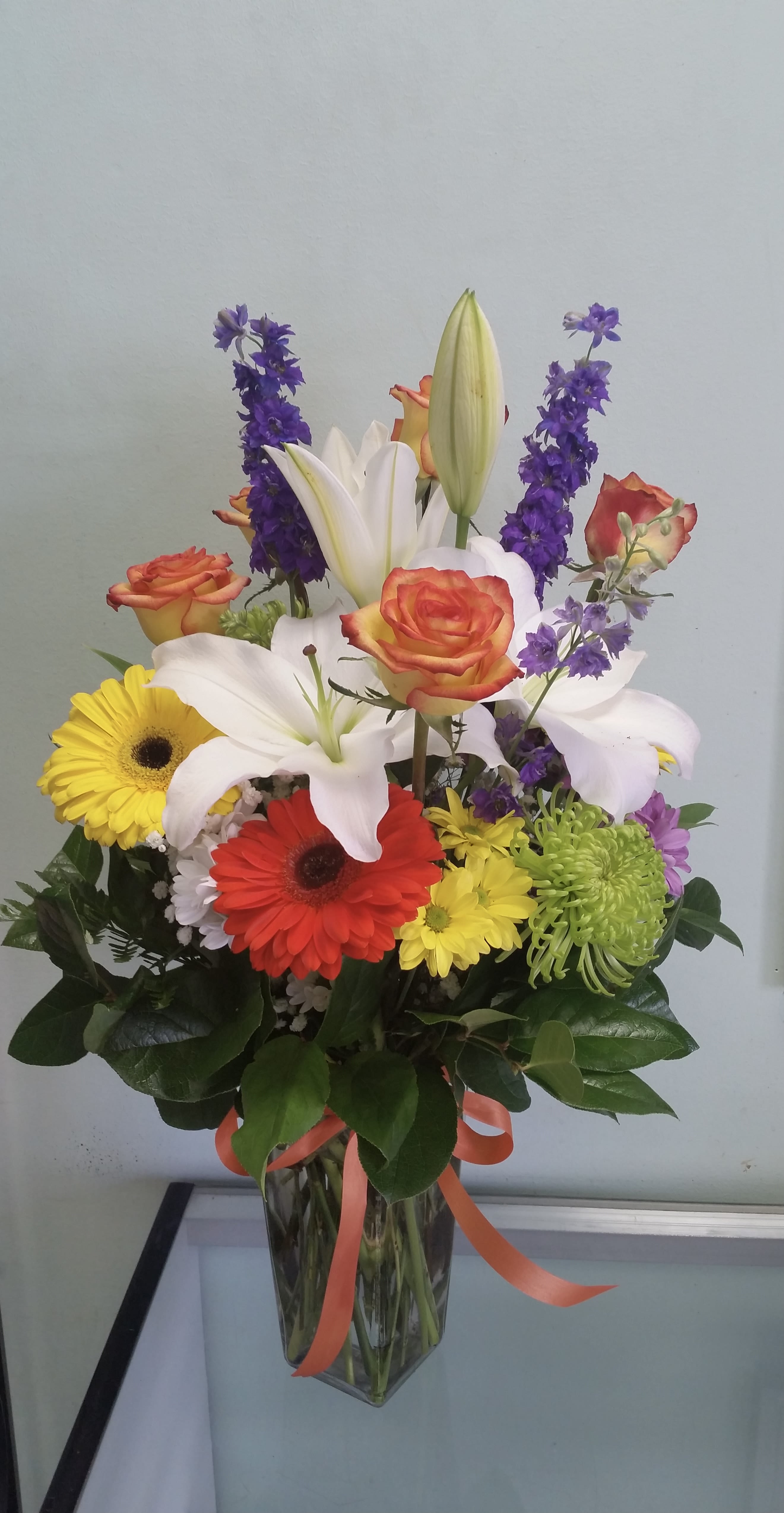 Colorful Celebration Colorful Celebration - Vase arrangement with gerbera daisies, lilies, mums, daisies, roses, and larkspurs.
