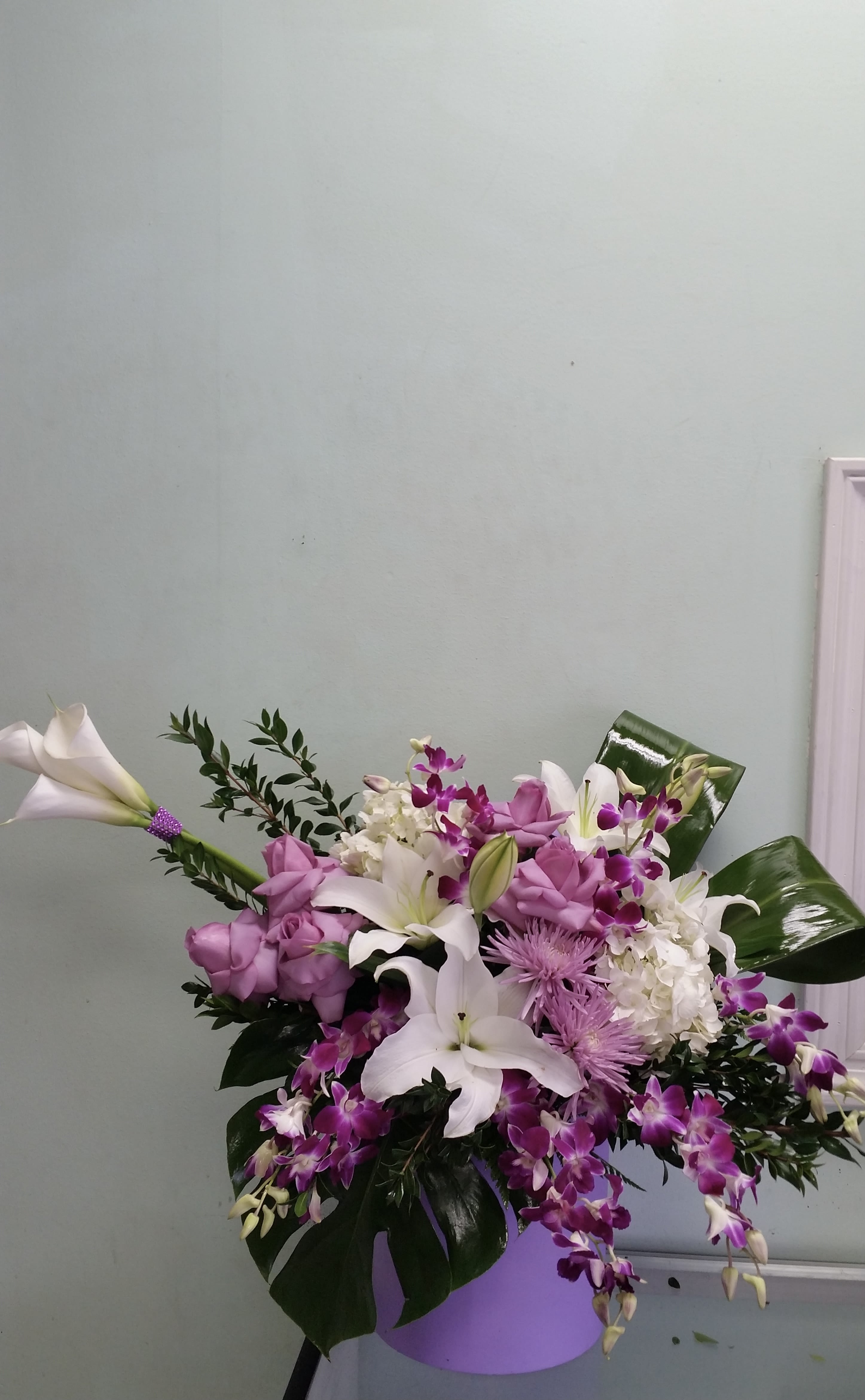 Purple Splash Purple Splash - Box arrangement with calla lilies, lillies, roses, mums, hydrangeas, and orchids.