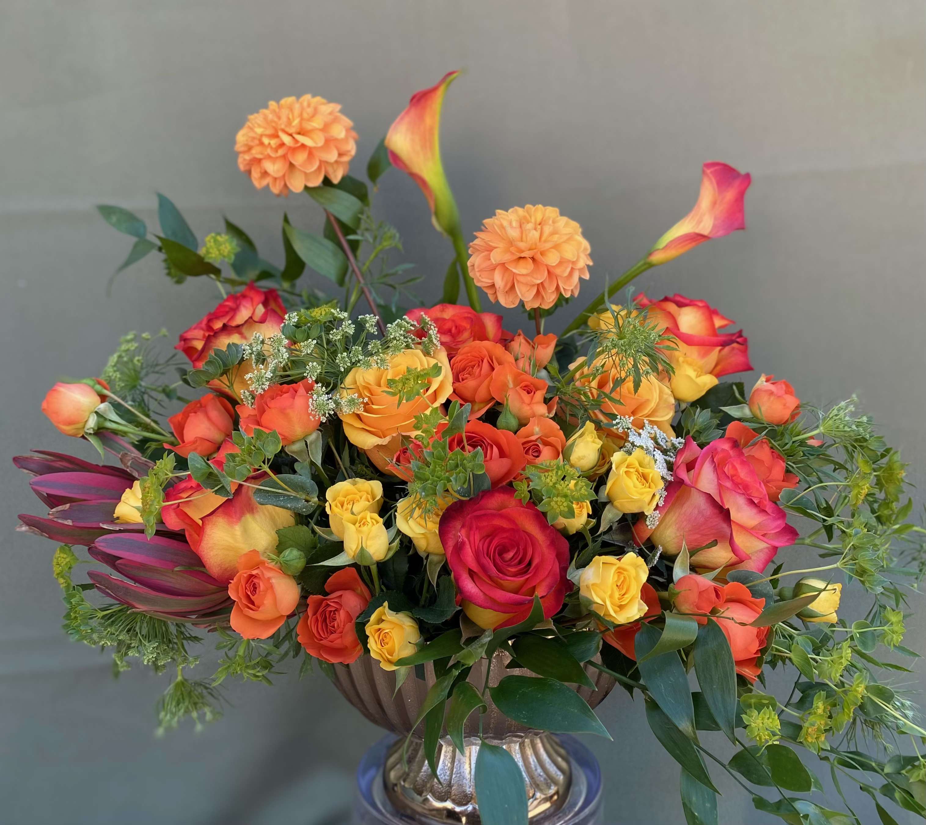 Glory Orange  - This very cheerful arrangement includes orange dahlias, calla lilies, mini spray roses, and yellow and orange roses, with green foliage all hand arrange an elegant vase.