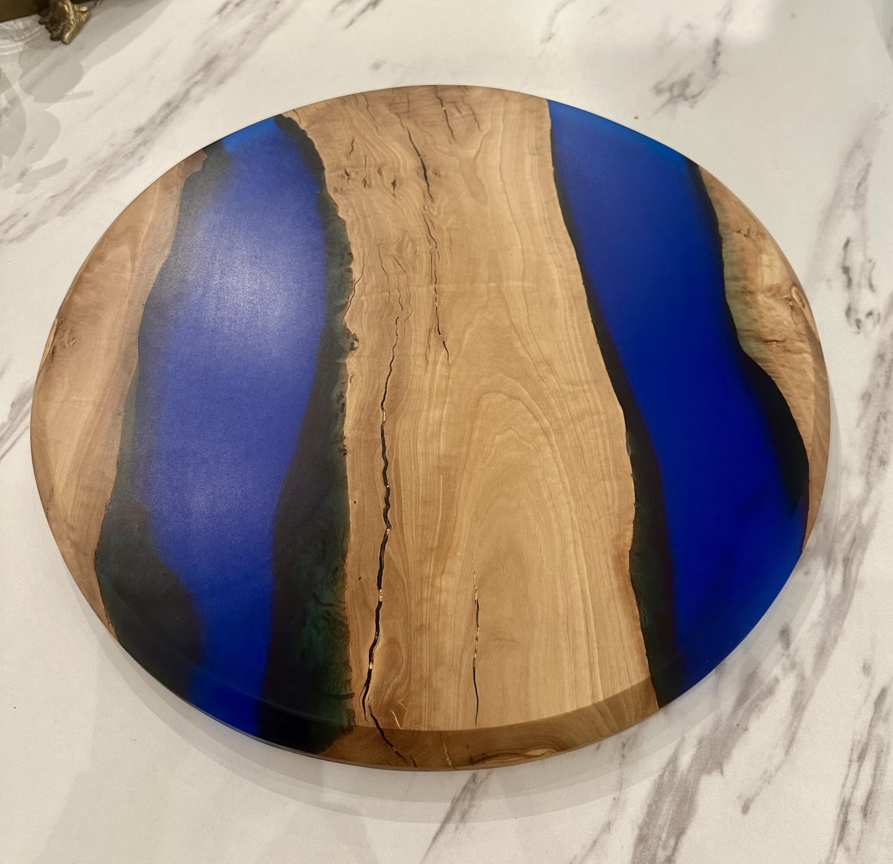 Wood Resin Lazy Susan - This stunning 15.5&quot; lazy Susan combines natural wood grain with glossy resin accents, making it both a functional and artistic addition to your dining table or kitchen. The wood's rich tones and organic textures are complemented by vibrant, swirling resin details, creating a striking contrast that draws the eye. Perfect for serving or as a decorative centerpiece, this lazy Susan rotates smoothly, allowing for easy access to condiments, snacks, or small dishes. Each piece is unique, showcasing the beauty of natural wood and the creativity of modern resin art, bringing elegance and style to any setting.  Exclusively made for Chartreuse by Roje by Dapperwood Atelier!
