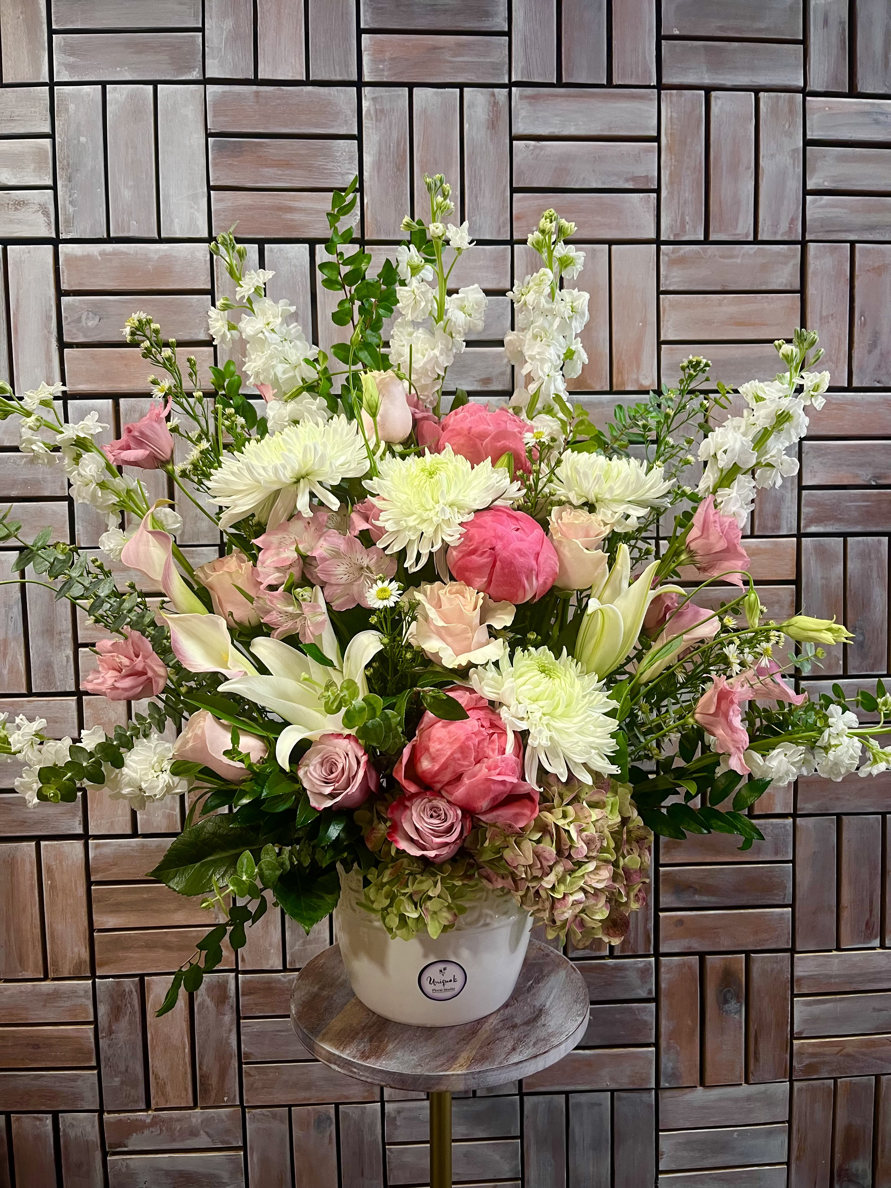 Graceful Farewell Basket by Unique K Floral Studio - The Graceful Farewell Basket is a beautiful pink and white tribute, perfect for honoring a loved one. Its timeless elegance makes it a fitting choice for any type of ceremony.