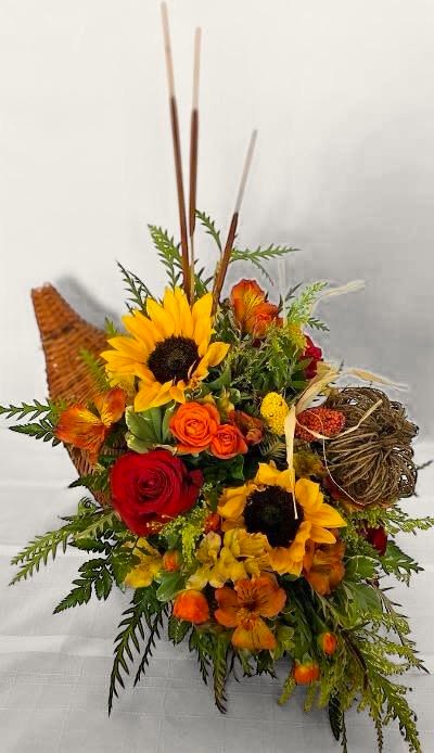 Thanksgiving Cornucopia Thanksgiving Cornucopia - This design is created in a traditional wicker Cornucopia just for your Thanksgiving table. It includes Roses, Spray Roses, Yellow and Orange Alstroemeria, Sunflowers, and Solidago. Accented with Cattails, a Wicker Pumpkin, and various other fall decorations for a traditional Cornucopia appeal. This design measures approx. 22"W x 21"H.