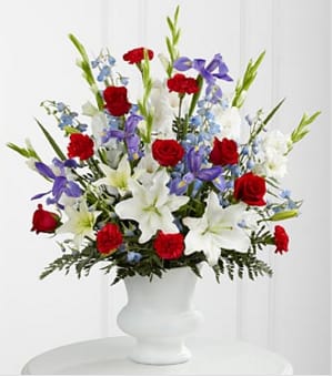 The Cherished Farewell Arrangement - The Cherished Farewell Arrangement is an elegant display of patriotic beauty to honor your loved one at their final farewell service. Red roses, red carnations, white gladiolus, light blue delphinium, blue iris, white Oriental lilies, white Asiatic lilies, and lush greens are elegantly arranged in a white plastic urn to create a stunning way to say your last goodbye. GOOD arrangement includes 28 stems. Approximately 32&quot;H x 26&quot;W Your purchase includes a complimentary personalized gift message.