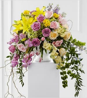 The Display of Affection Arrangement - The Display of Affection Arrangement is an exquisite way to commemorate the life of the deceased. Lavender roses, yellow stock, pink stock, pink tulips, yellow roses, pink roses, pink spray roses, lavender larkspur, Bells of Ireland, yellow freesia, yellow Asiatic lilies, blue delphinium, green hydrangea and lush greens are accented with curly willow branches and arranged to create a sophisticated display that radiates elegance and grace at their final farewell service.