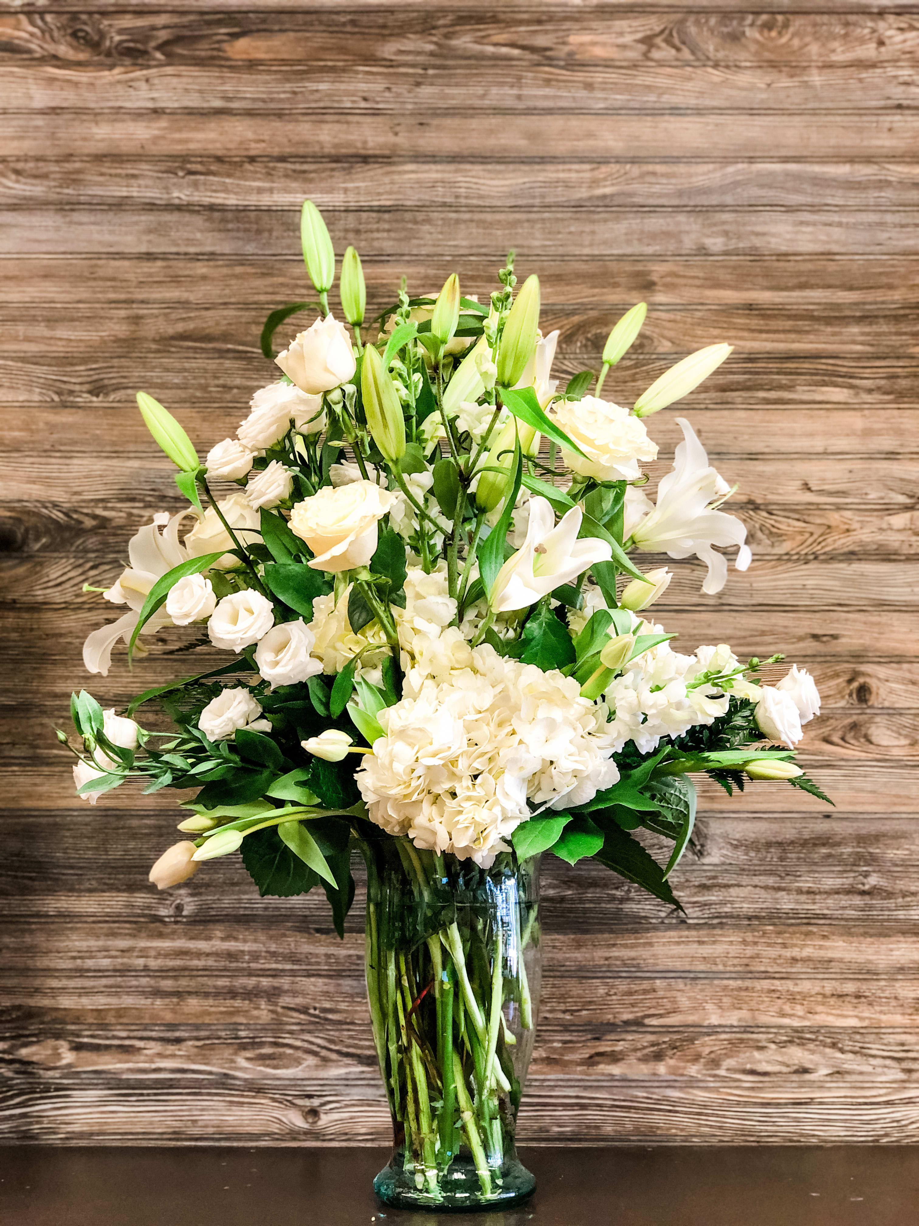 Our Sympathy - All white mix of seasonal flowers.  Roses, Hydrangeas, Lillies mixes with other seasonal white flowers. Those flower varieties may change with what's in season. As shown ~ Premium Price  