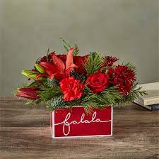 YULETIDE CAROL BOUQUET YULETIDE CAROL BOUQUET - Deck their halls with this lively bouquet studded with surprising red lilies and a jolly keepsake box that captures the joy of the season.