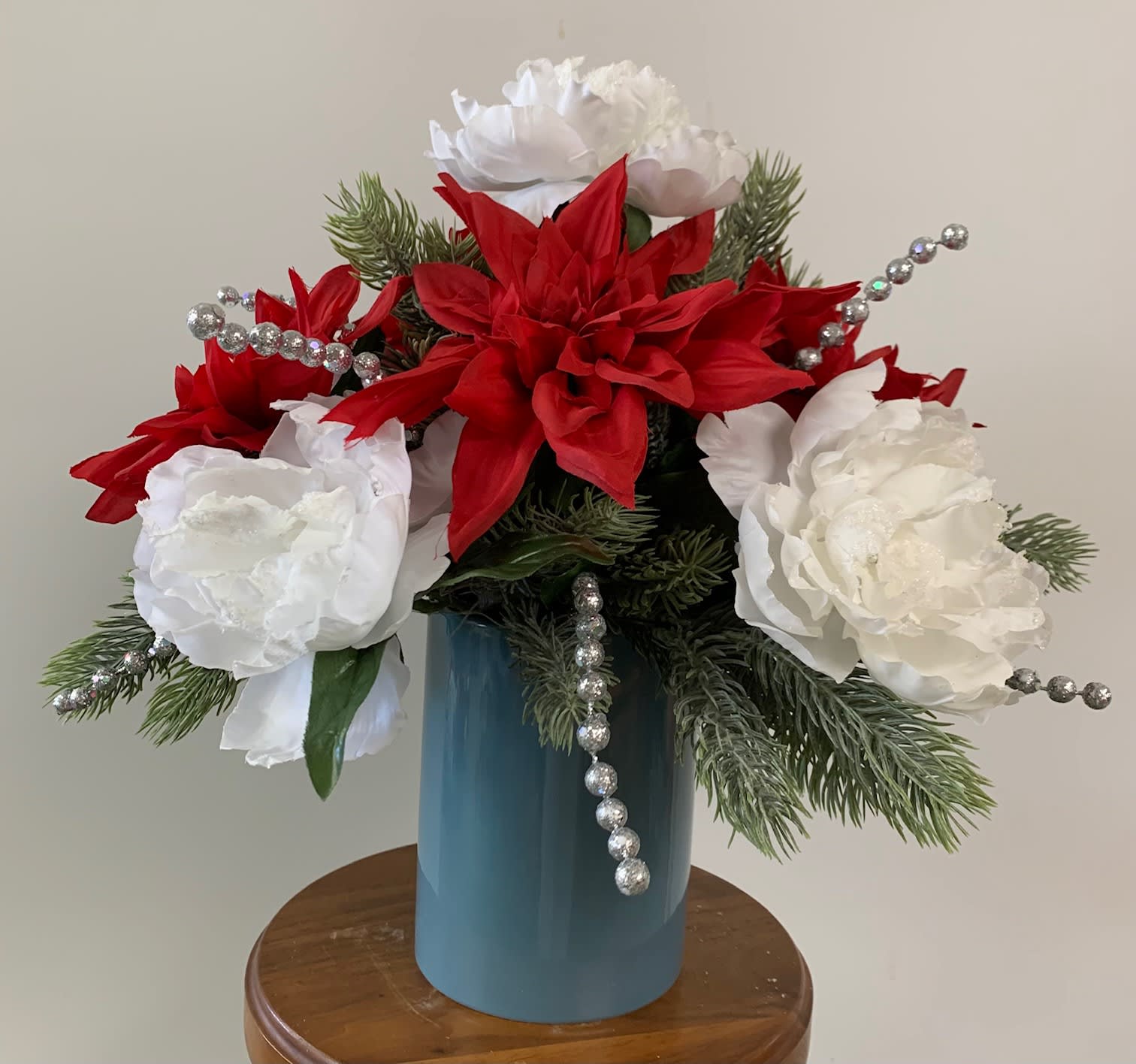 Silk Christmas Silk Christmas - Silk arrangement in red, white, and silver in a blue ceramic vase.