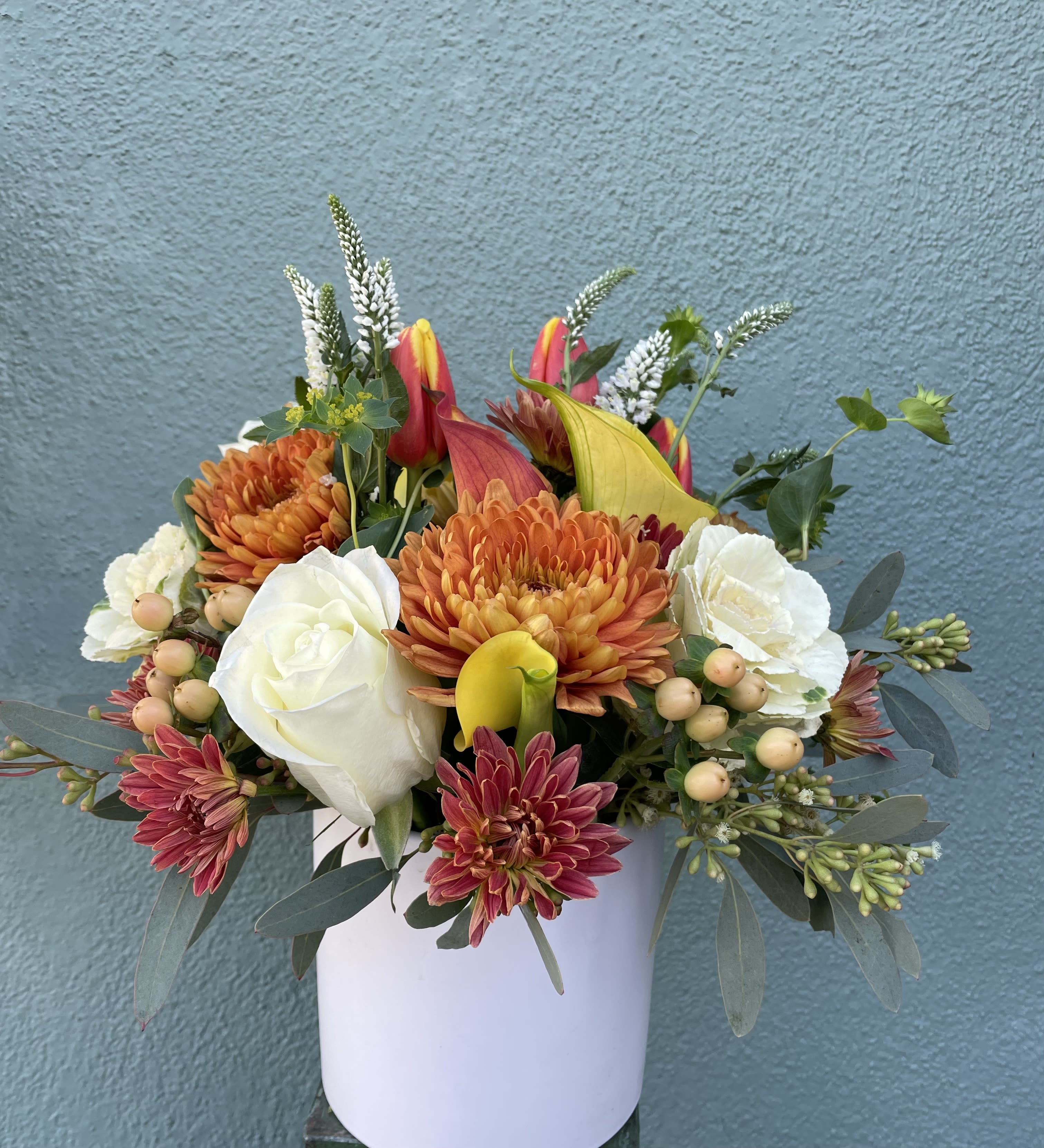 Cutie Autumn Cutie Autumn - This floral arrangement includes mini calla lilies, roses chrysanthemums, coffee beans, green foliage, all hand arranged in white vase.