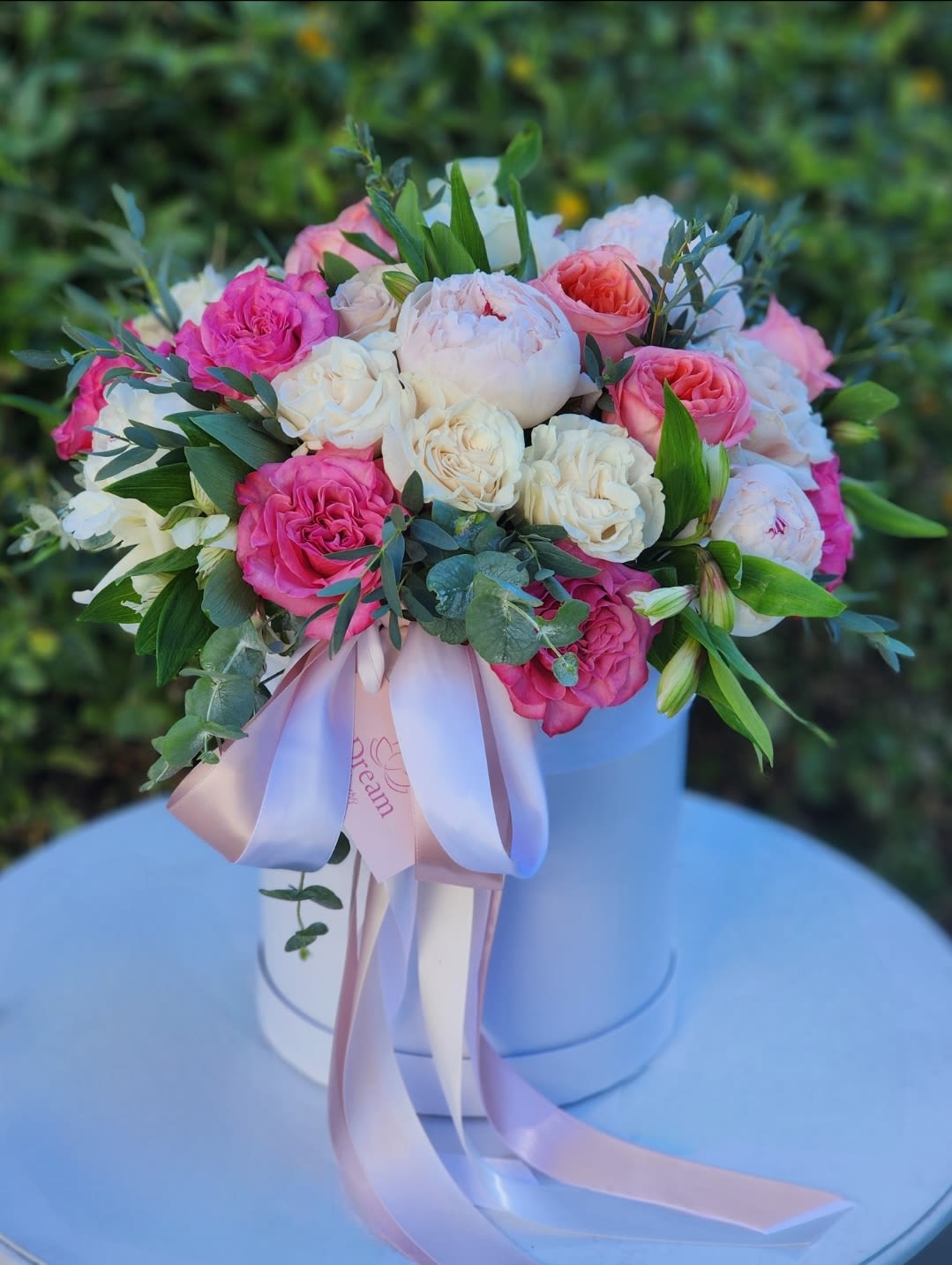 Soft Palette - The arrangement in white hatbox features a stunning mix of flowers, including white and pink roses, blush peonies, creating a harmonious blend of soft and light colors. Whether it's a special occasion or just because.