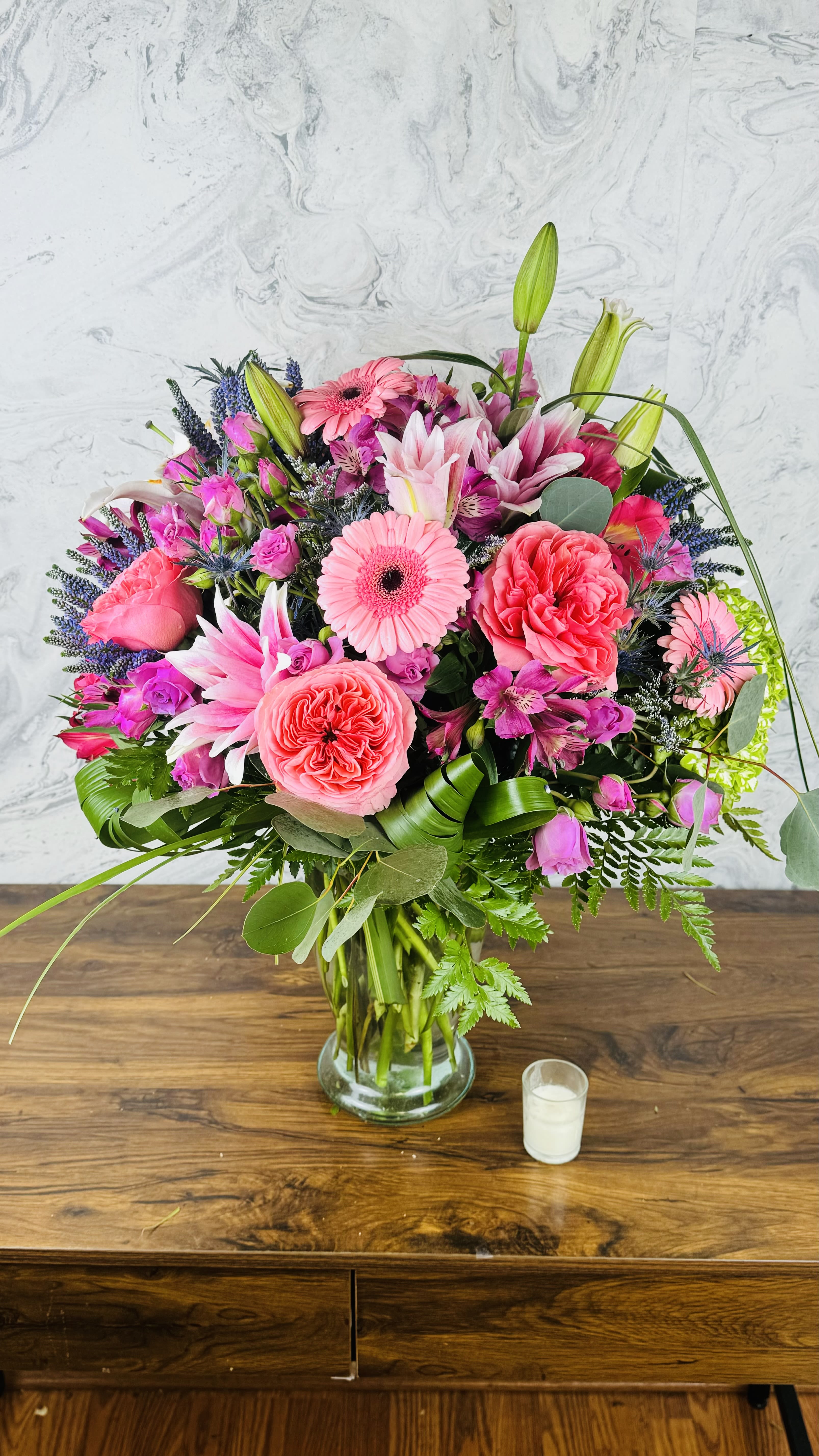 Vibrant Celebration - This stunning floral arrangement features a vibrant mix of blooms in an array of colors, expertly combined to create a striking focal point for any occasion. With its large size and diverse selection of flowers, it radiates joy and elegance, making it perfect for celebrations, gatherings, or simply brightening up any space. Each flower is thoughtfully chosen to complement the others, ensuring a lively and cheerful display that captures the beauty of nature in full bloom.